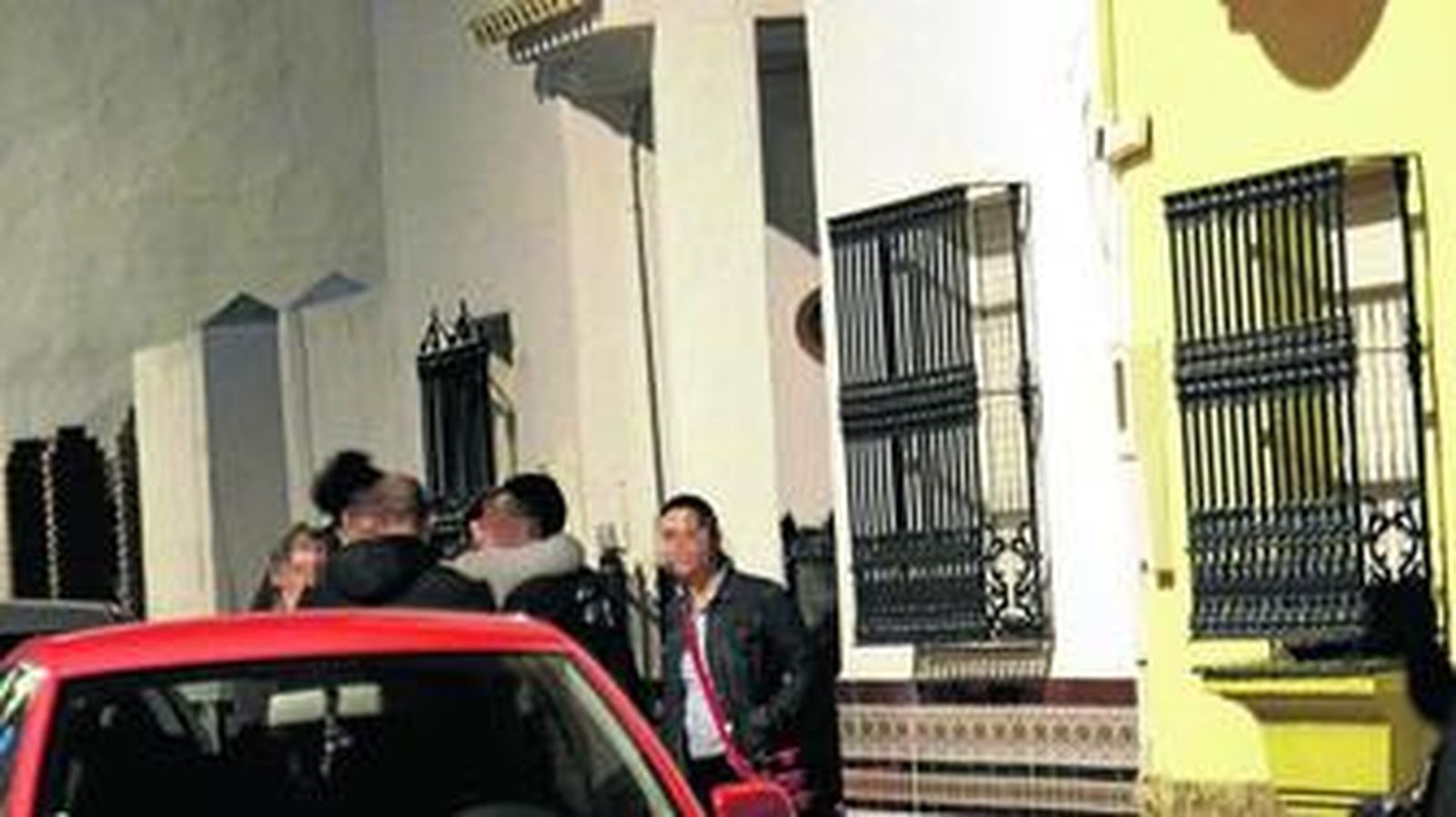 Familiares se abrazan en la puerta de la vivienda donde se produjo la agresión.