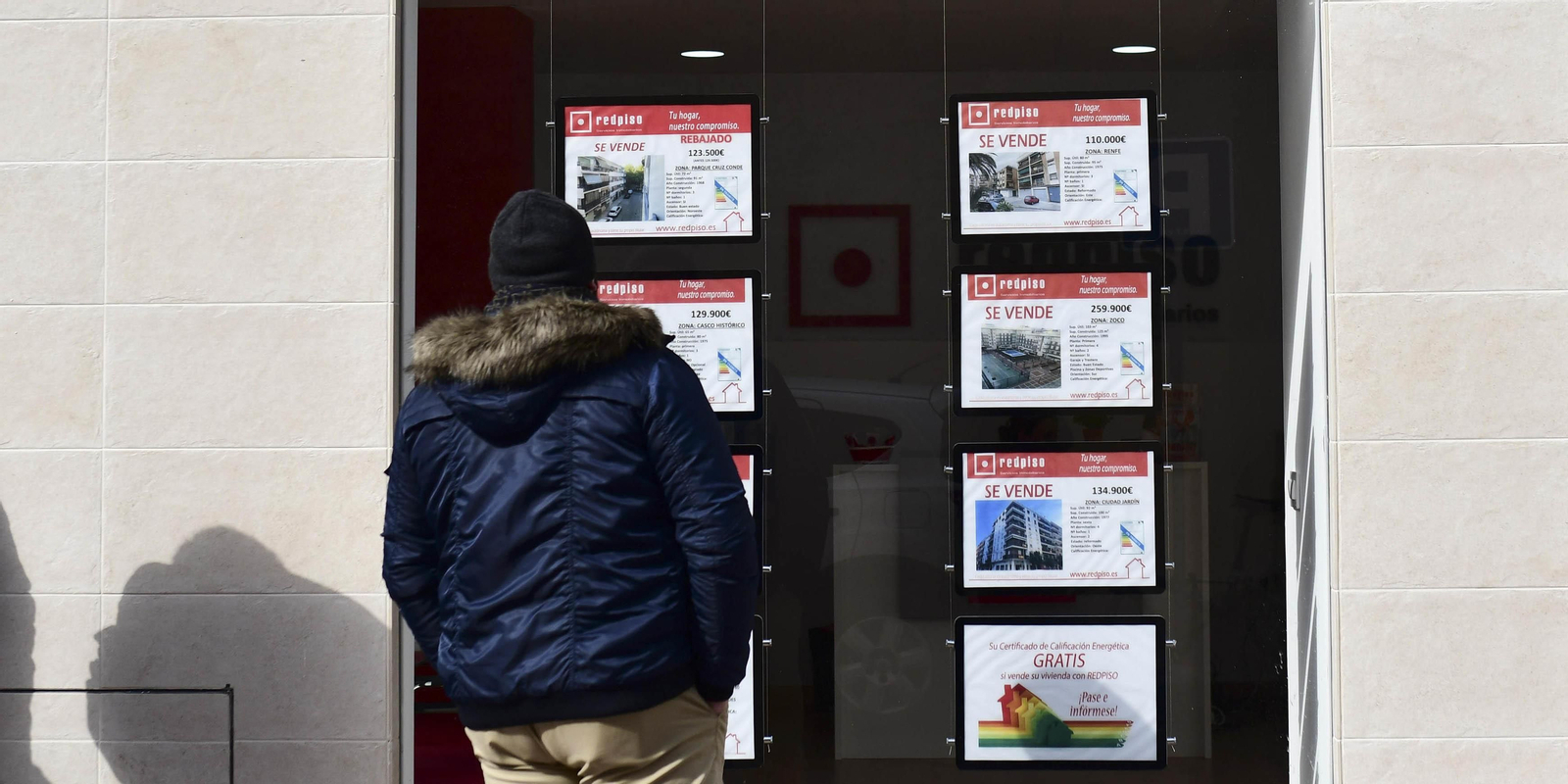 Un joven mira anuncios en el escaparate de una inmobiliaria