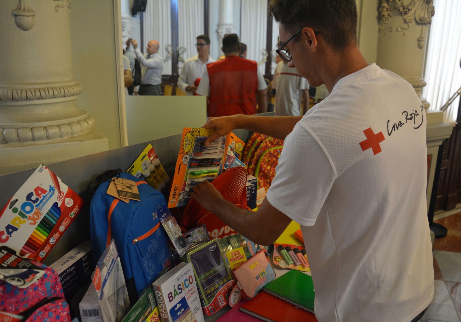Uno de los voluntarios de Cruz Roja con algunos de los materiales escolares que se van a donar.