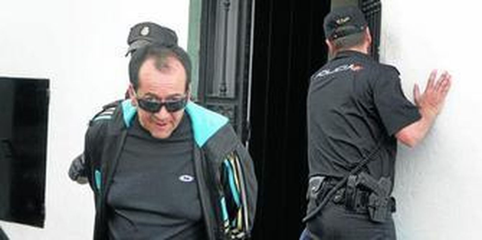 El detenido es conducido por agentes de la Policía hacia un coche patrulla una vez detenido en el piso de la calle Trafalgar.