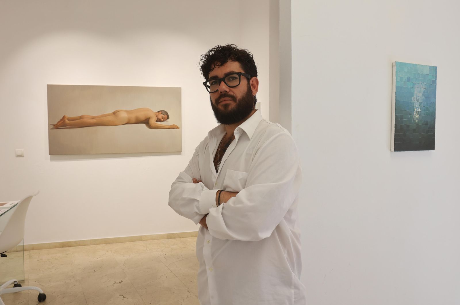 Guillermo Amaya Brenes, codirector de la galería Domo, posa ante las obras de Juan Manuel Rodríguez.