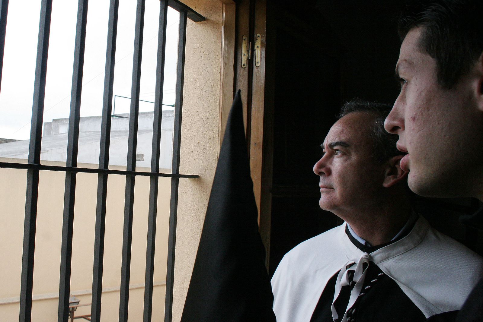 Nazarenos mirando por la ventana para observar el estado del tiempo.