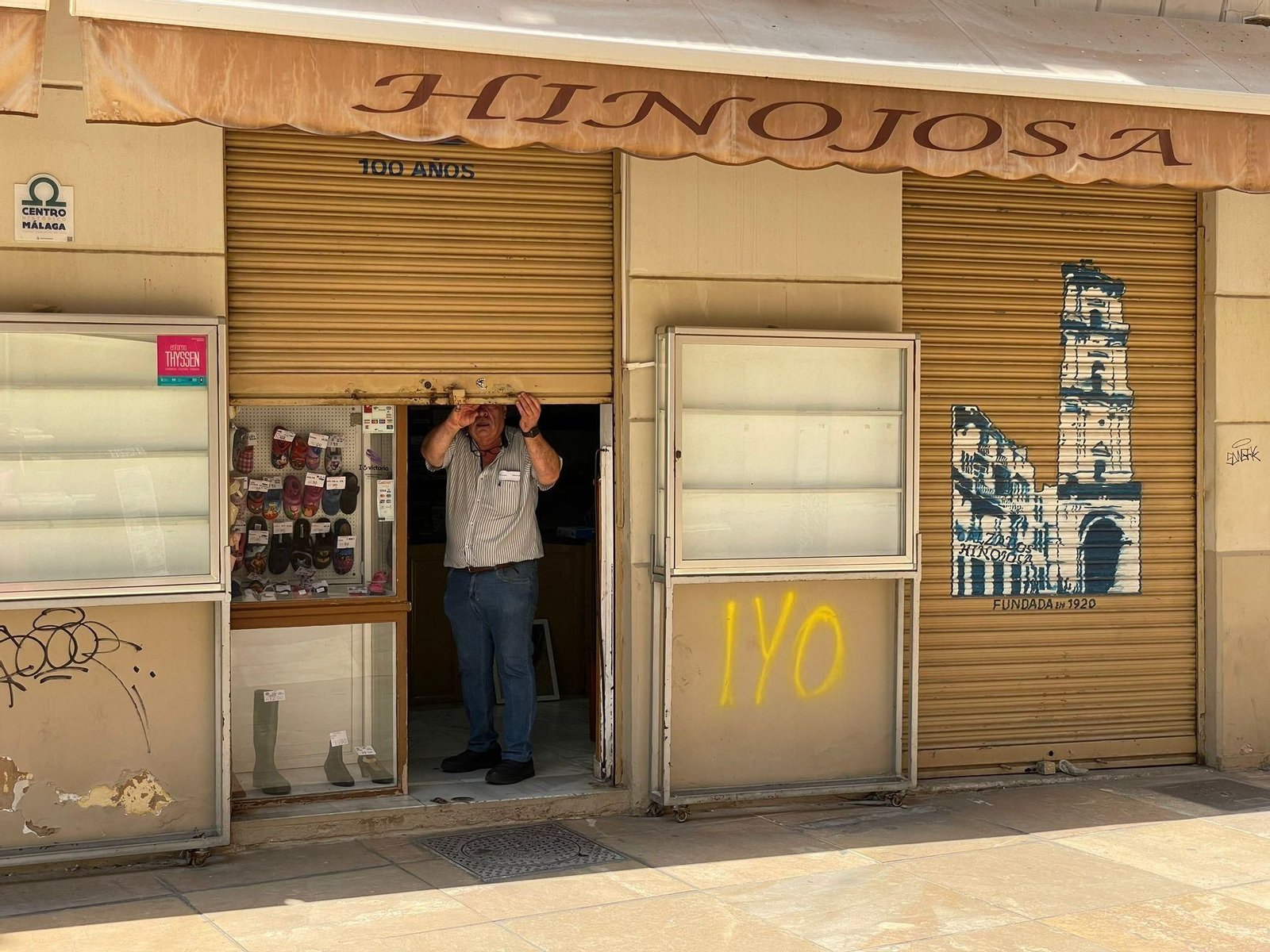 Uno de los propietarios de Calzados Hinojosa echa la verja metálica por última vez este mediodía.
