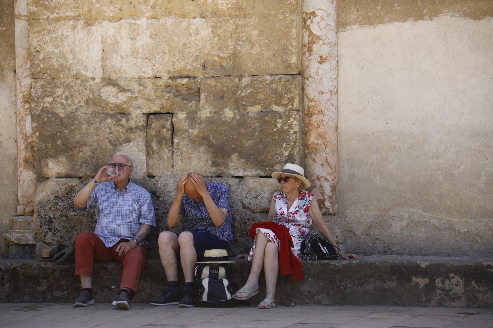 Un grupo de turistas se protege del calor a la sombra en los alrededores de la Mezquita-Catedral.