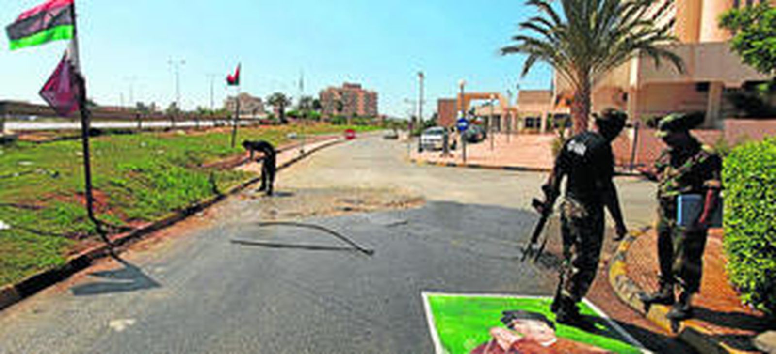 Un rebelde libio charla con un colega mientras pisa un póster de Gadafi en la ciudad de Bengasi.