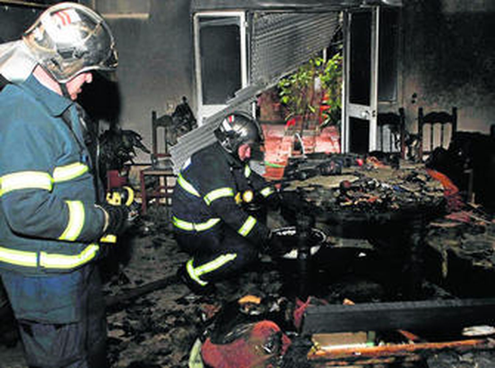Los bomberos comprueban el estado del salón donde se originó el incendio, que quedó calcinado.