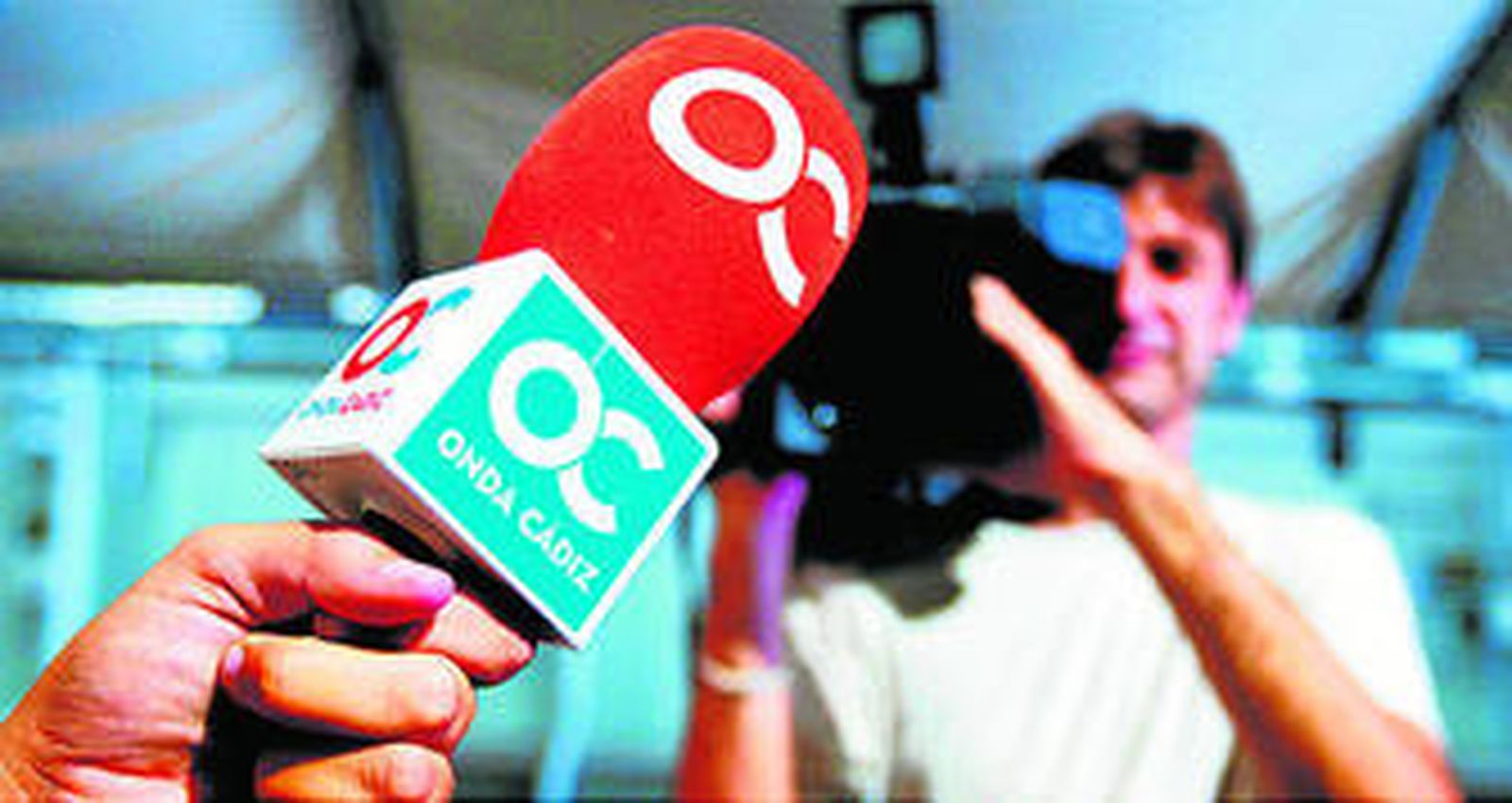 Un micrófono de Onda Cádiz enfocado por una cámara en segundo plano.