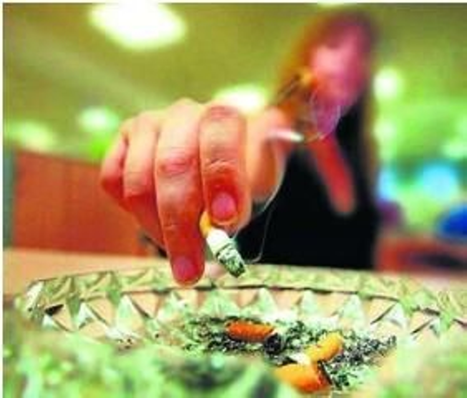 Una fumadora se dispone a apagar un cigarro en un cenicero.