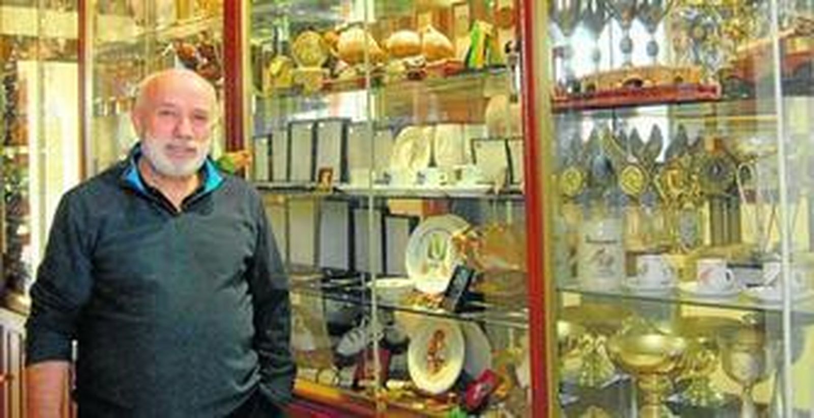 José Antonio Espinosa posa, con su agaporni Kiwi en el hombro, junto a numerosos trofeos conseguidos en sus años dedicada a los canarios de postura.