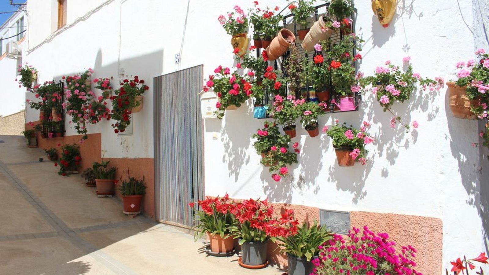 Calles engalanadas con geranios, sobre las paredes de las típicas casas blancas