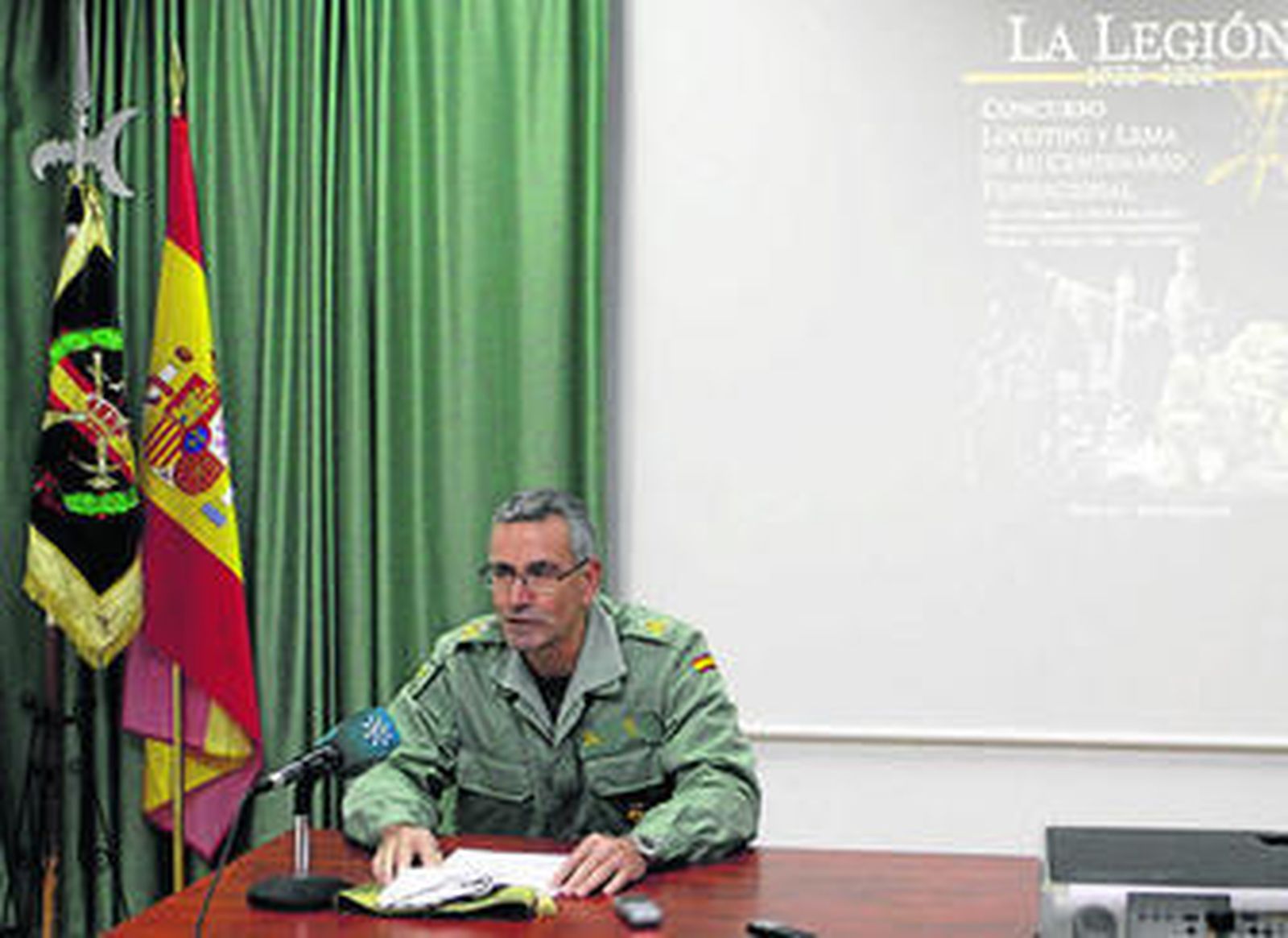 El general Leza, jefe de la BRILEG, durante la presentación del concurso con el cartel conmemorativo al fondo.