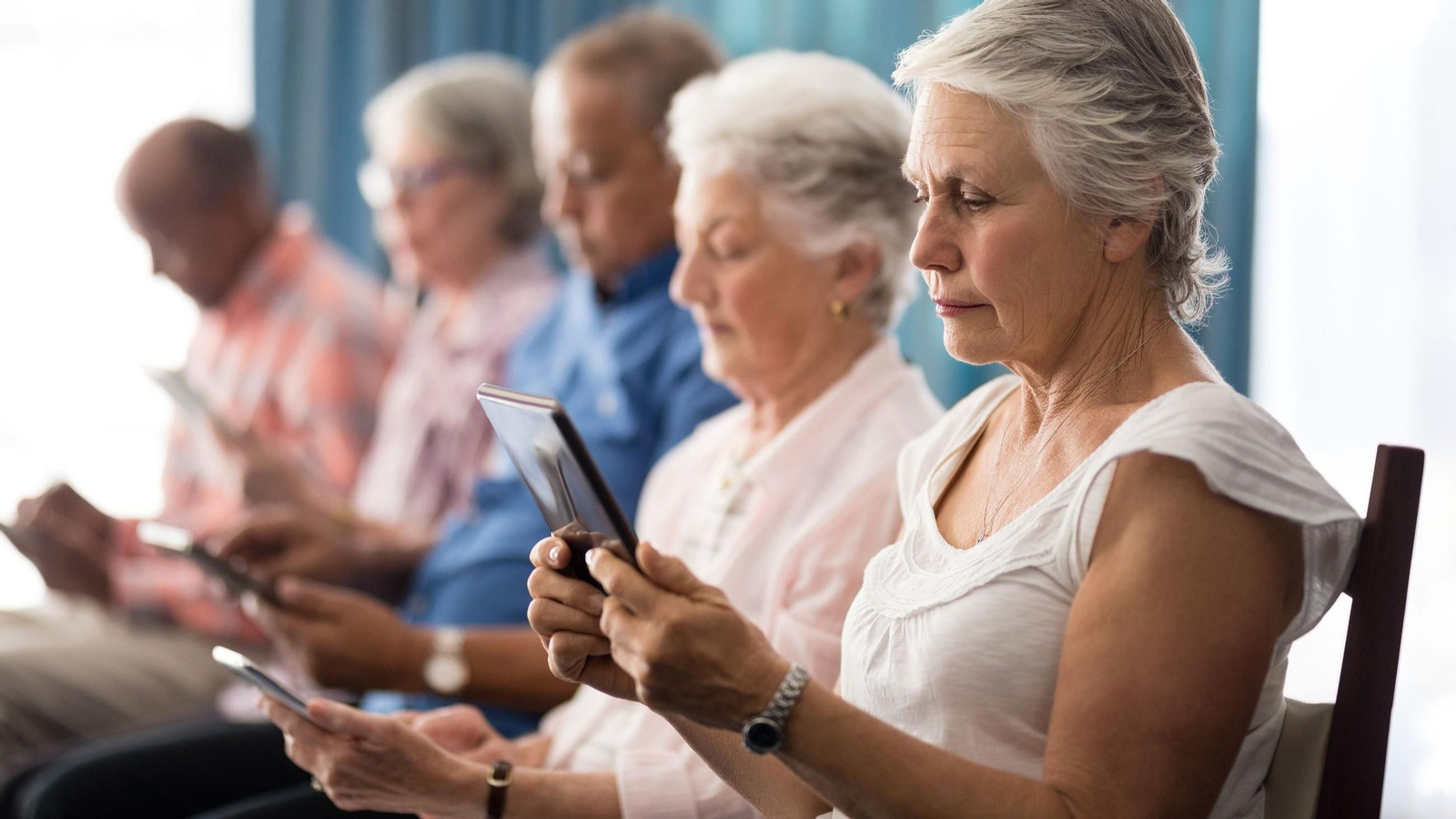 Imagen de archivo de mayores con móviles y tablets en un curso.