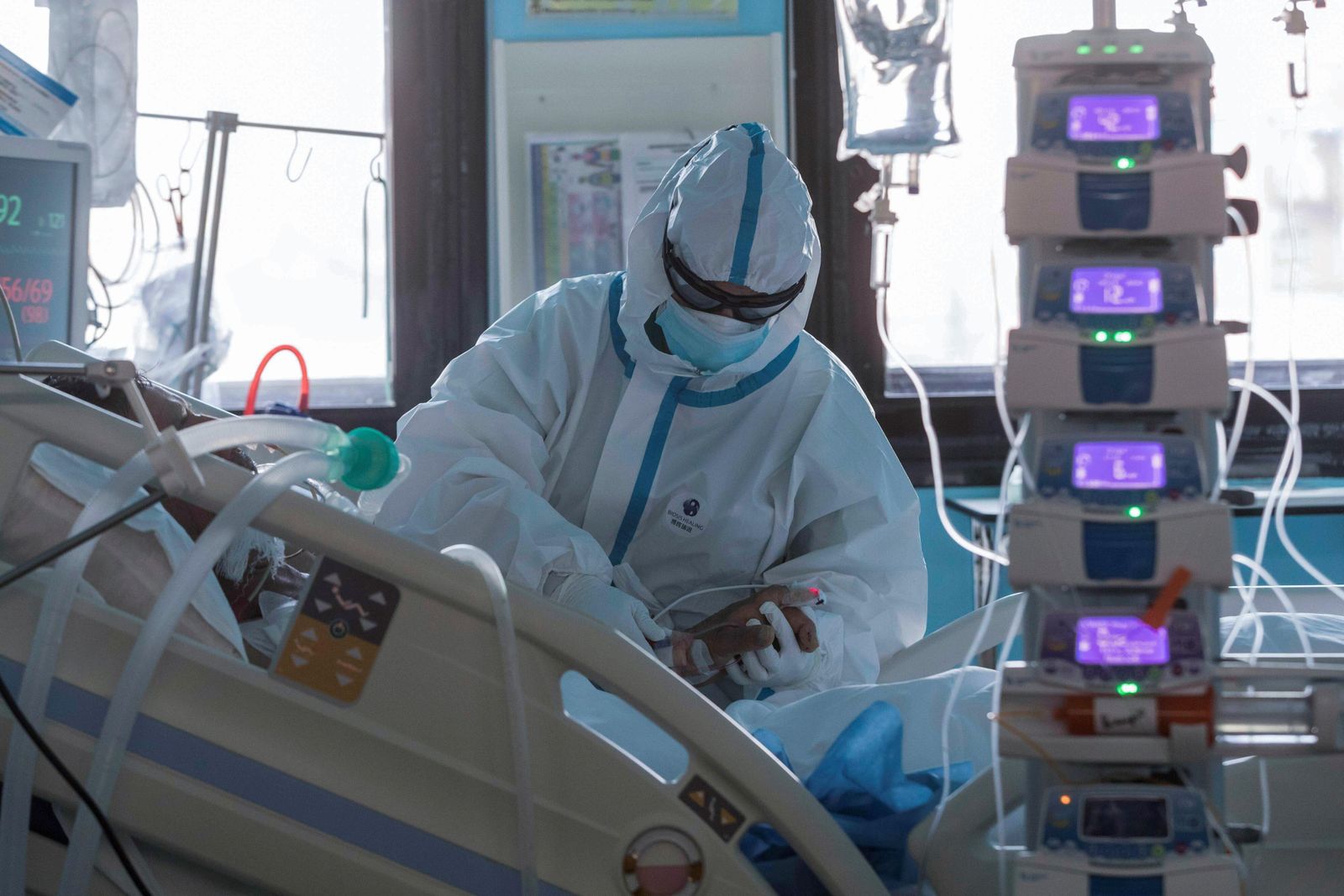 Un profesional sanitario atiende a un paciente en una UCI.