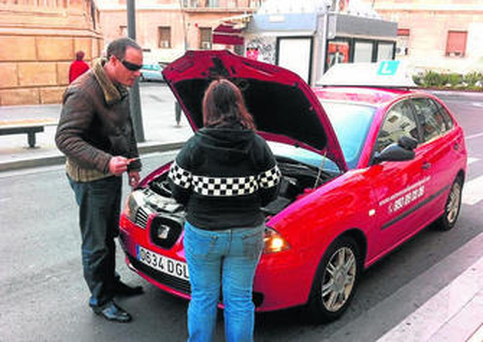 Un profesor explica a su alumna cómo debe mirar el nivel de aceite.
