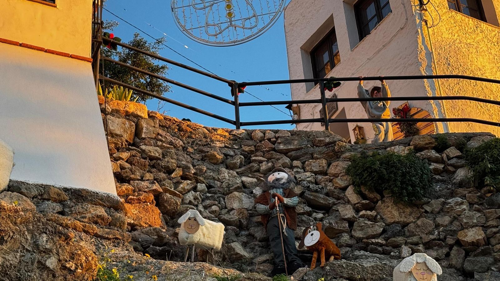 Un niño observa desde arriba a un pastor con sus ovejas