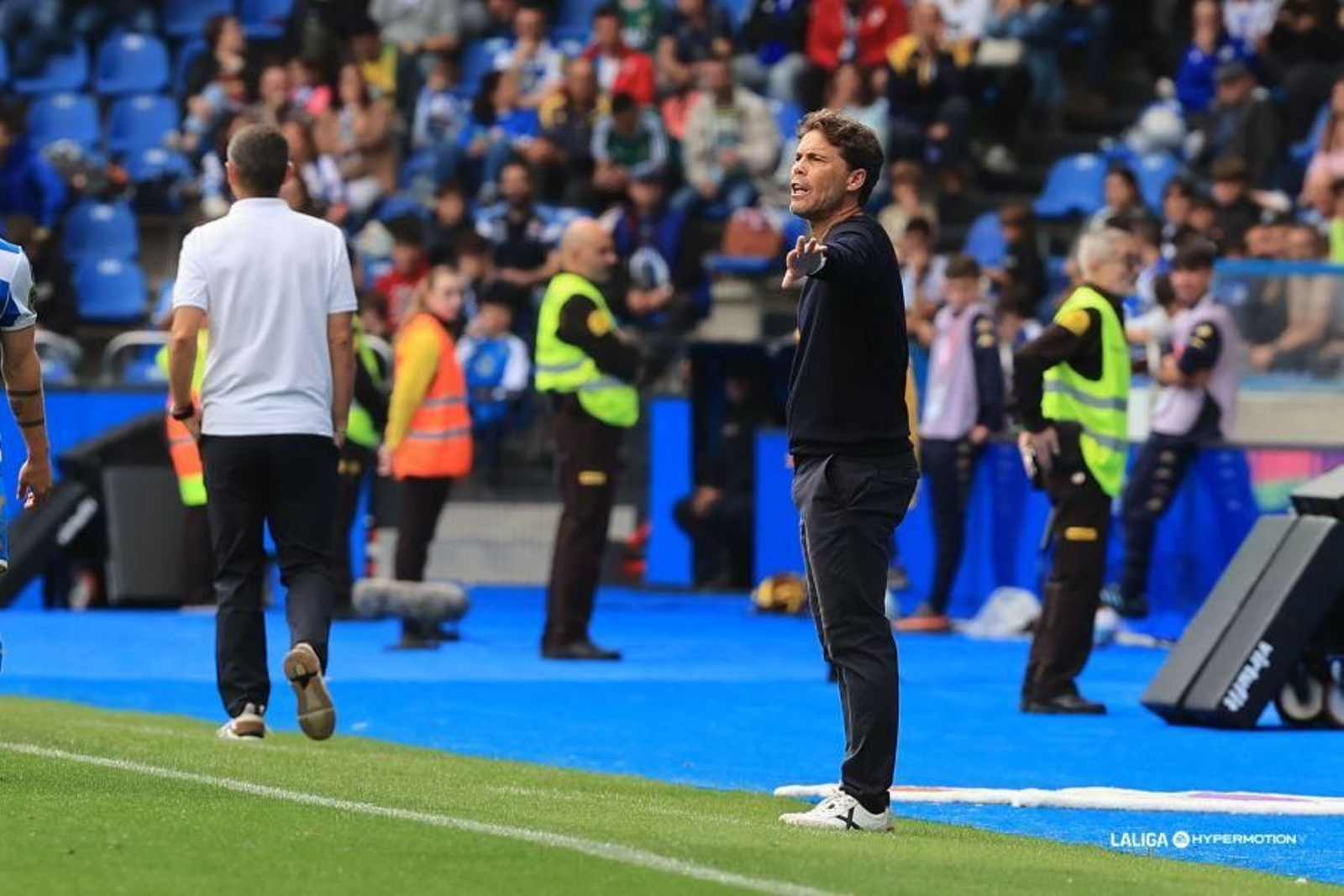 Rubi realiza una indicación desde la banda a sus futbolistas con Antonio Hidalgo, técnico de los gallegos, de espaldas.