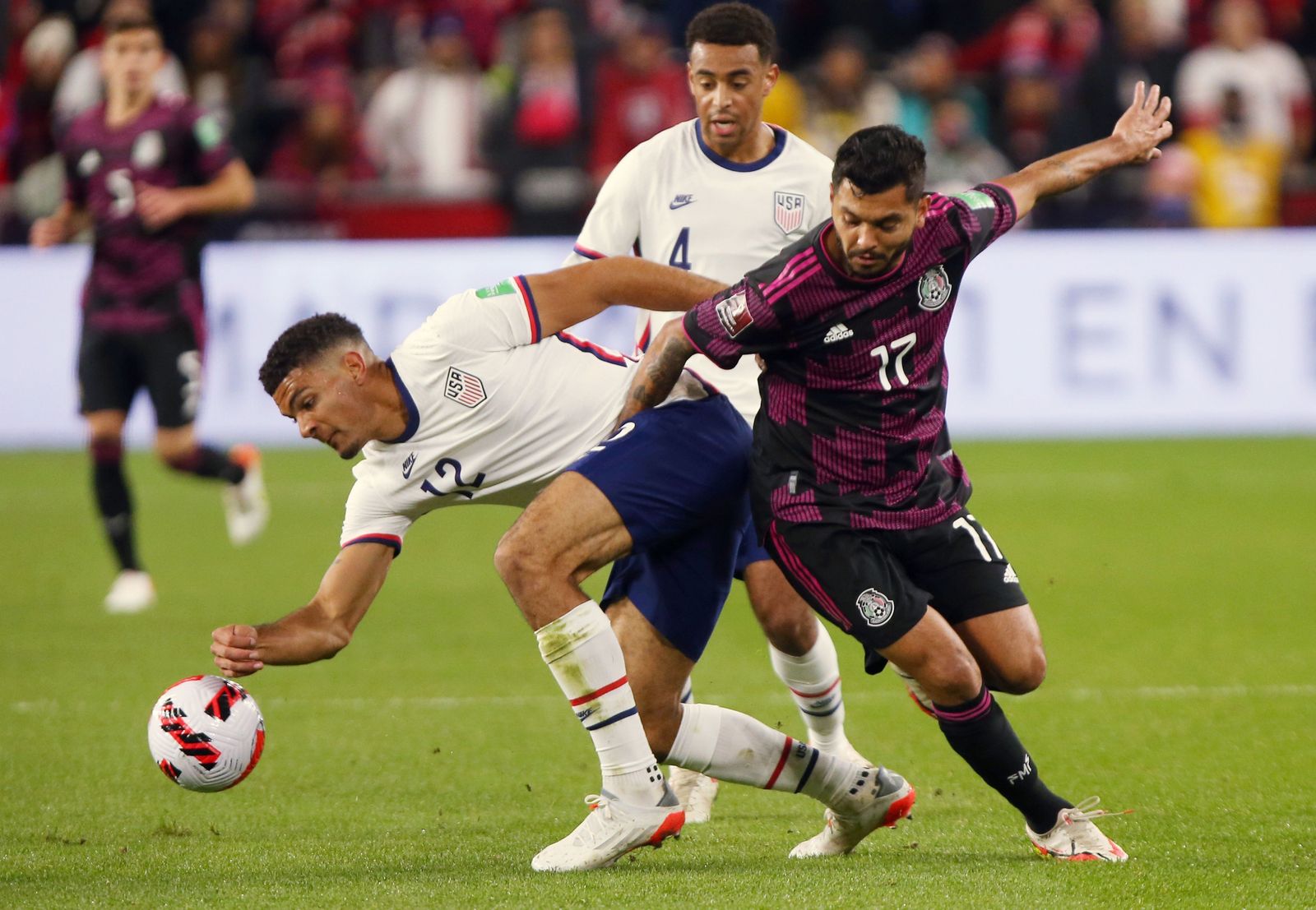 Tecatito Corona disputa un balón ante un rival en el EEUU-México.