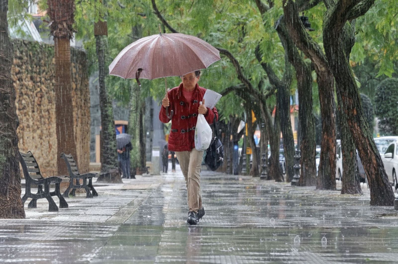 Una persona se refugia de la lluvia en Huelva con un paraguas.