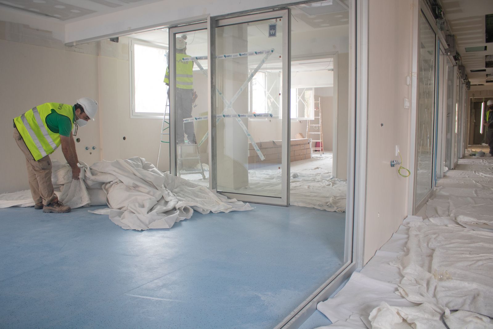 Dos operarios trabajan en los últimos retoques en los nuevos boxes de la UCI del Virgen del Rocío.