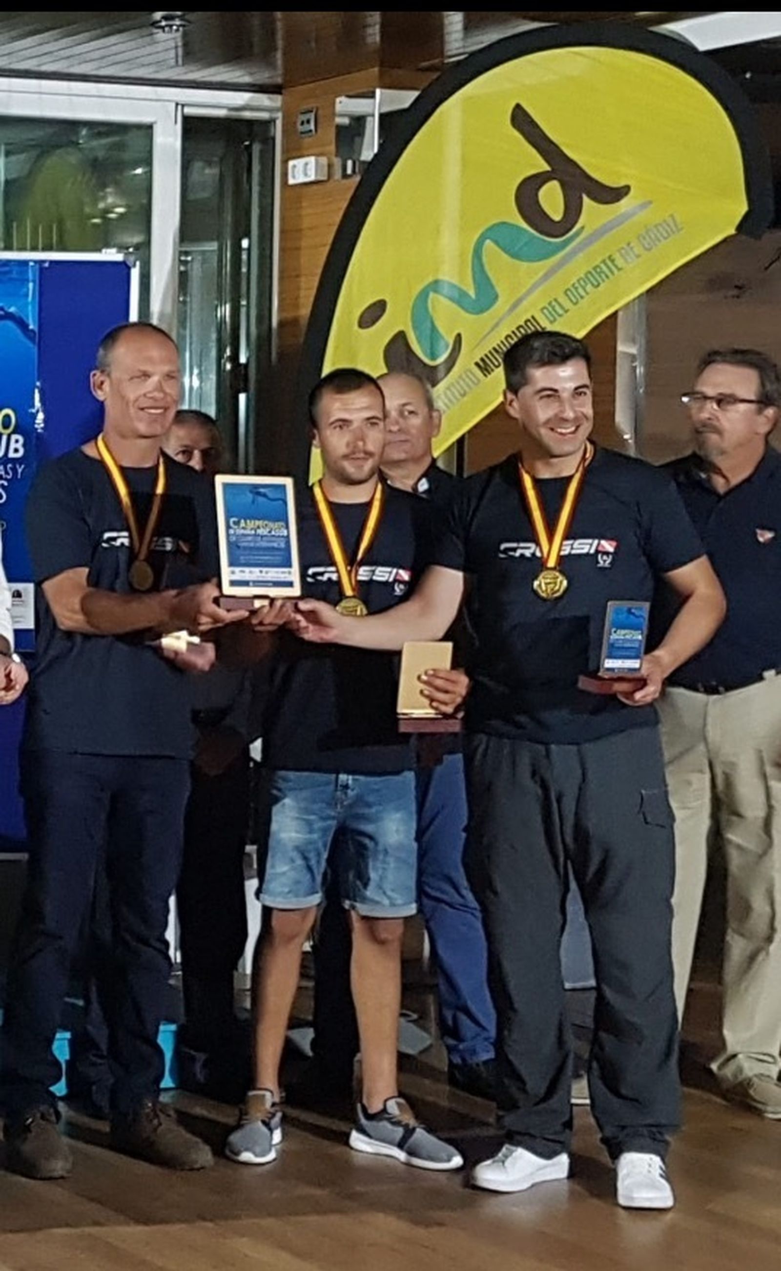 Los componentes del trío campeón posan con sus medallas y galardones.