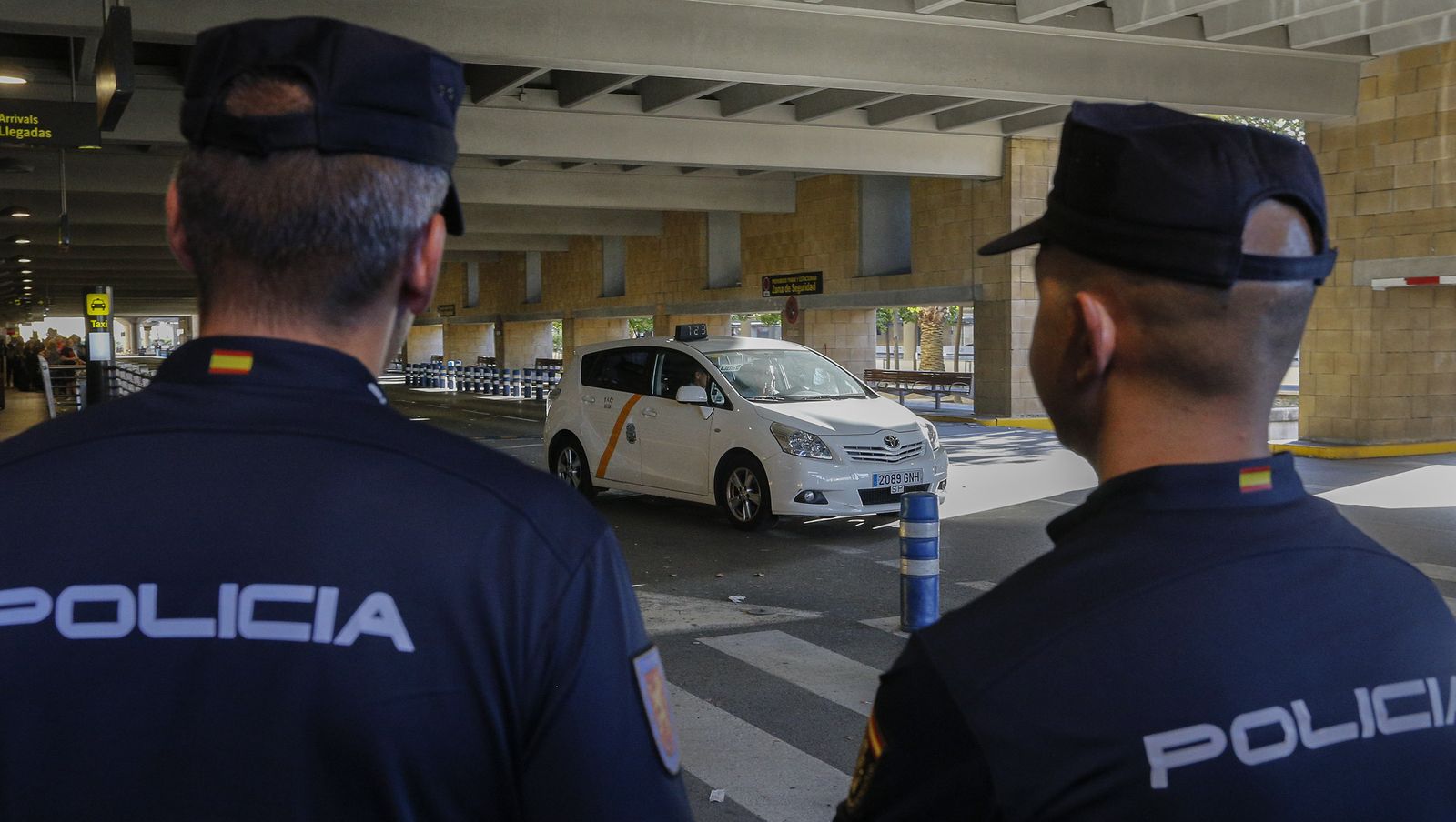 Dos agentes de la Policía Nacional observan un taxi en el aeropuerto.