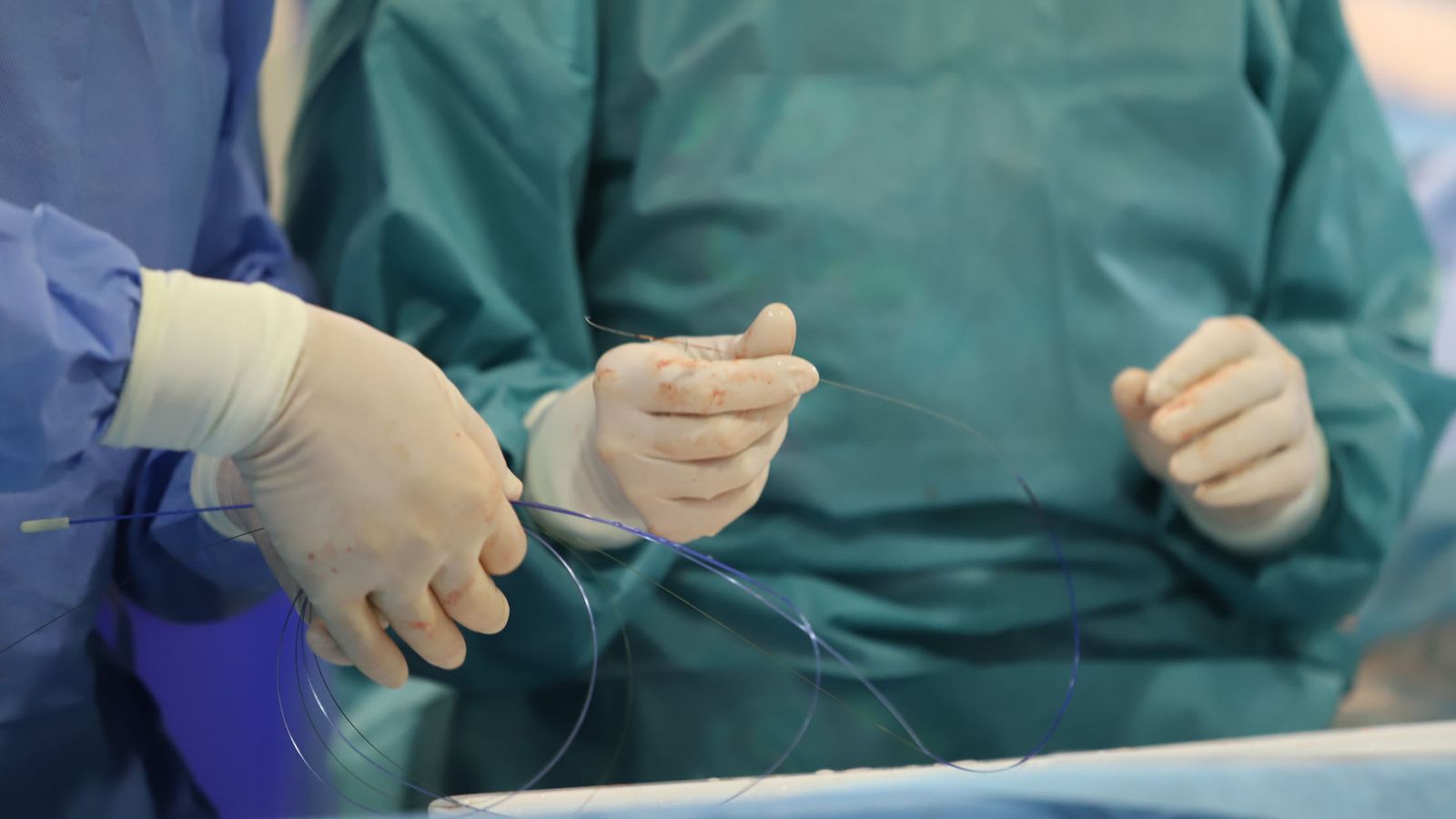 Catéter en el momento de ser introducido en el paciente, es sostenido por médicos.