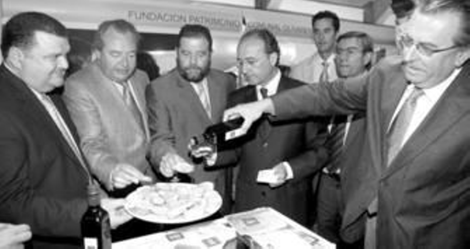 El presidente de la Denominación de Origen Montoro-Adamuz, Francisco Terán, riega pan con aceite de oliva para que lo degusten los cargos públicos.