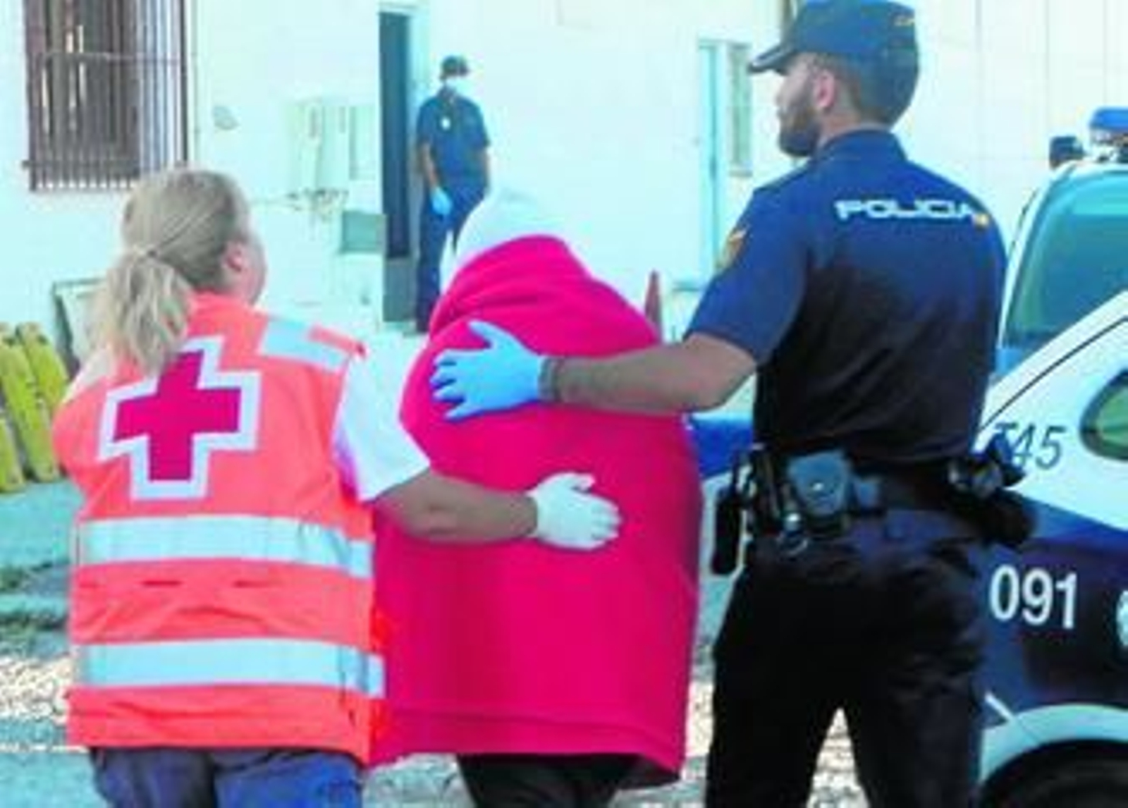Un voluntario de Cruz Roja y un agente del Cuerpo Nacional de Policía asisten a una persona a su llegada a puerto. Un voluntario de Cruz Roja y un agente del Cuerpo Nacional de Policía asisten a una persona a su llegada a puerto.