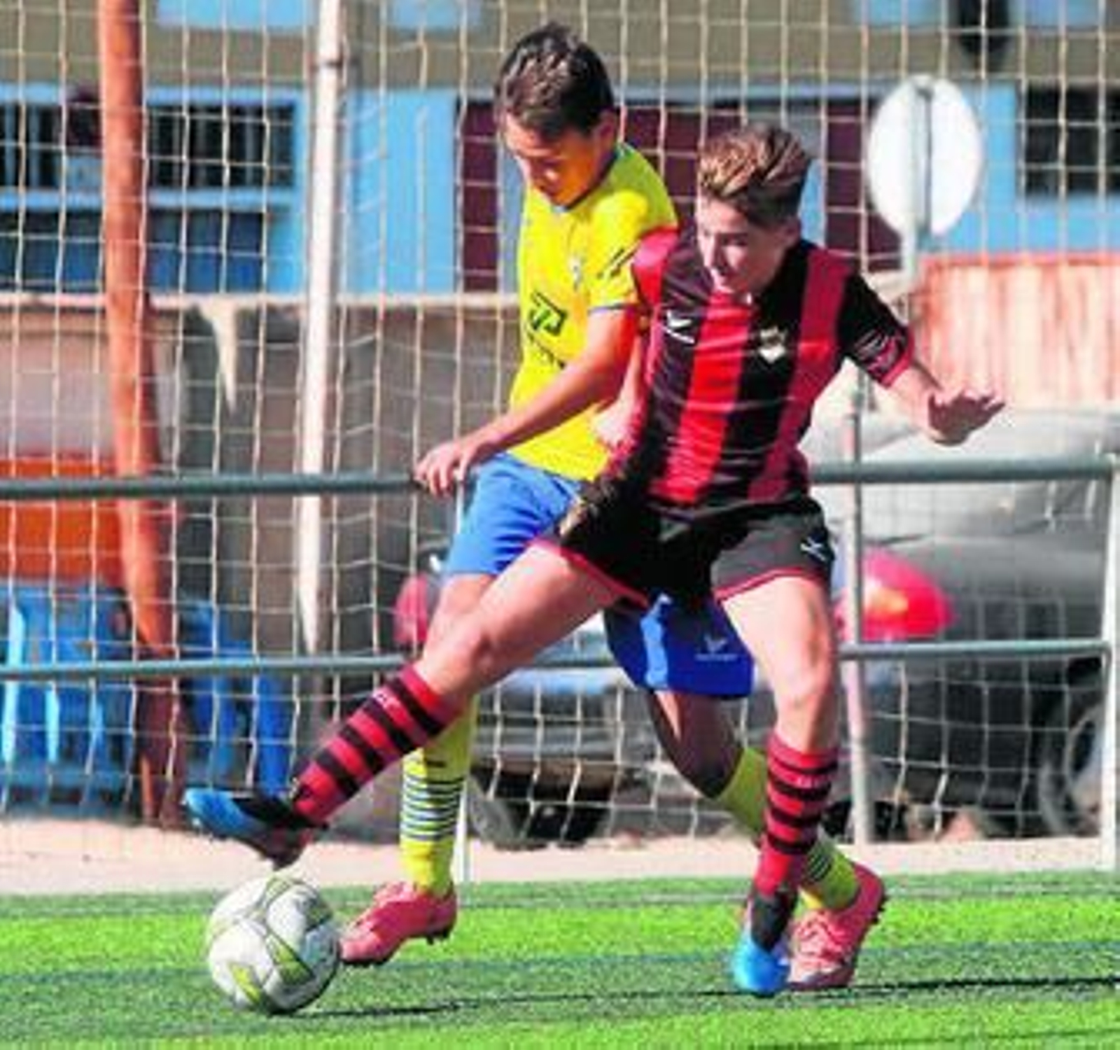 Un rojinegro se lleva el balón ante un jugador del Tomares.