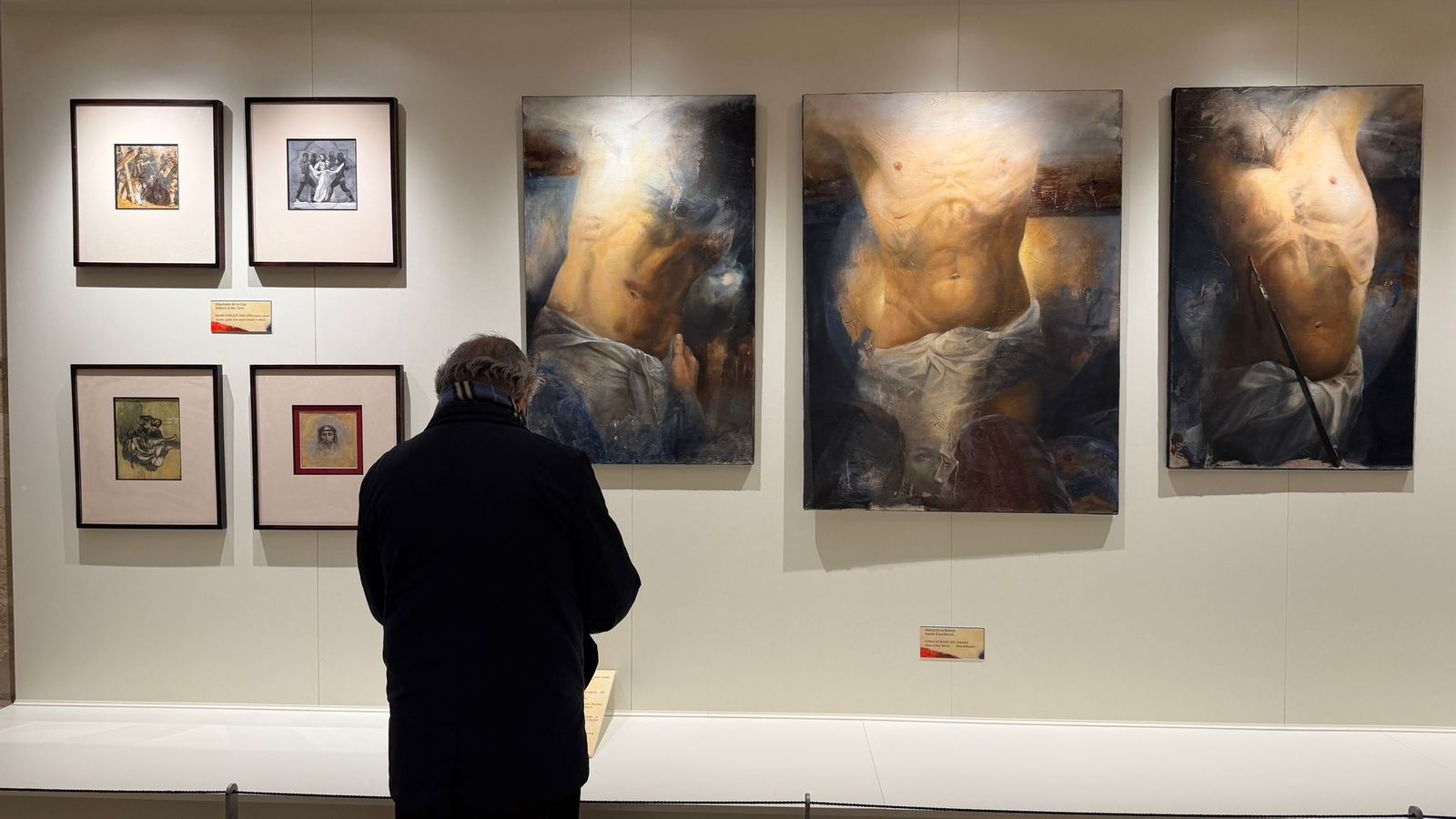 Un hombre observa varios de los cuadros de la exposición.