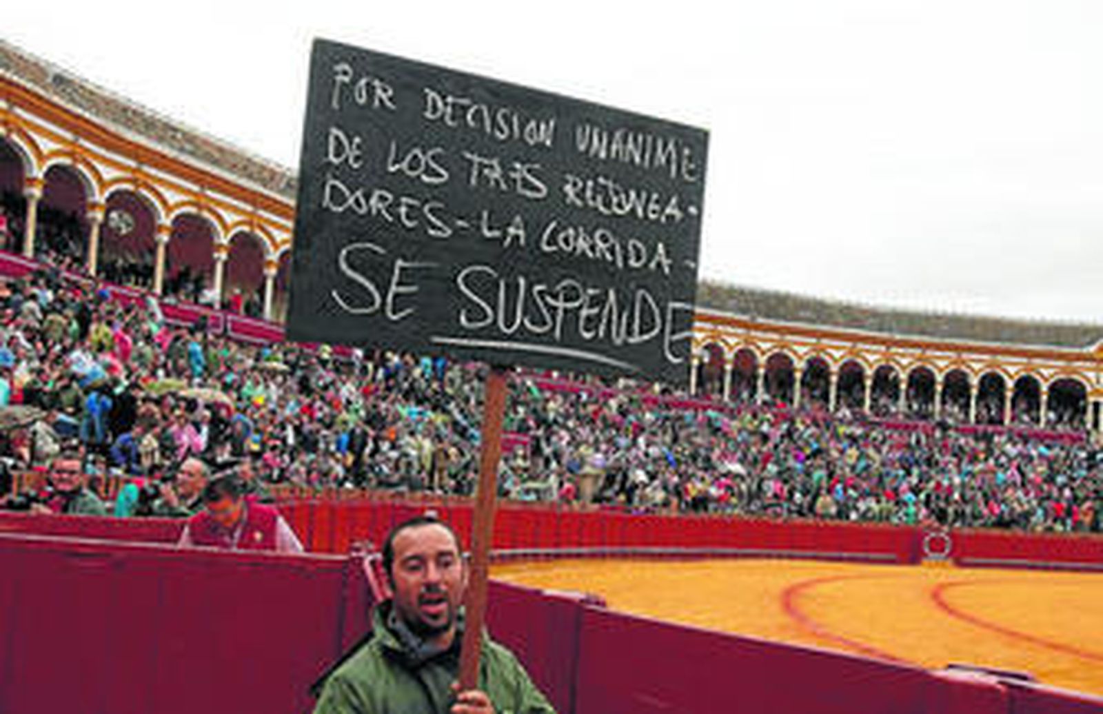 Momento en el que un empleado de la plaza pasea por el callejón la anacrónica pizarra con el anuncio de suspensión.