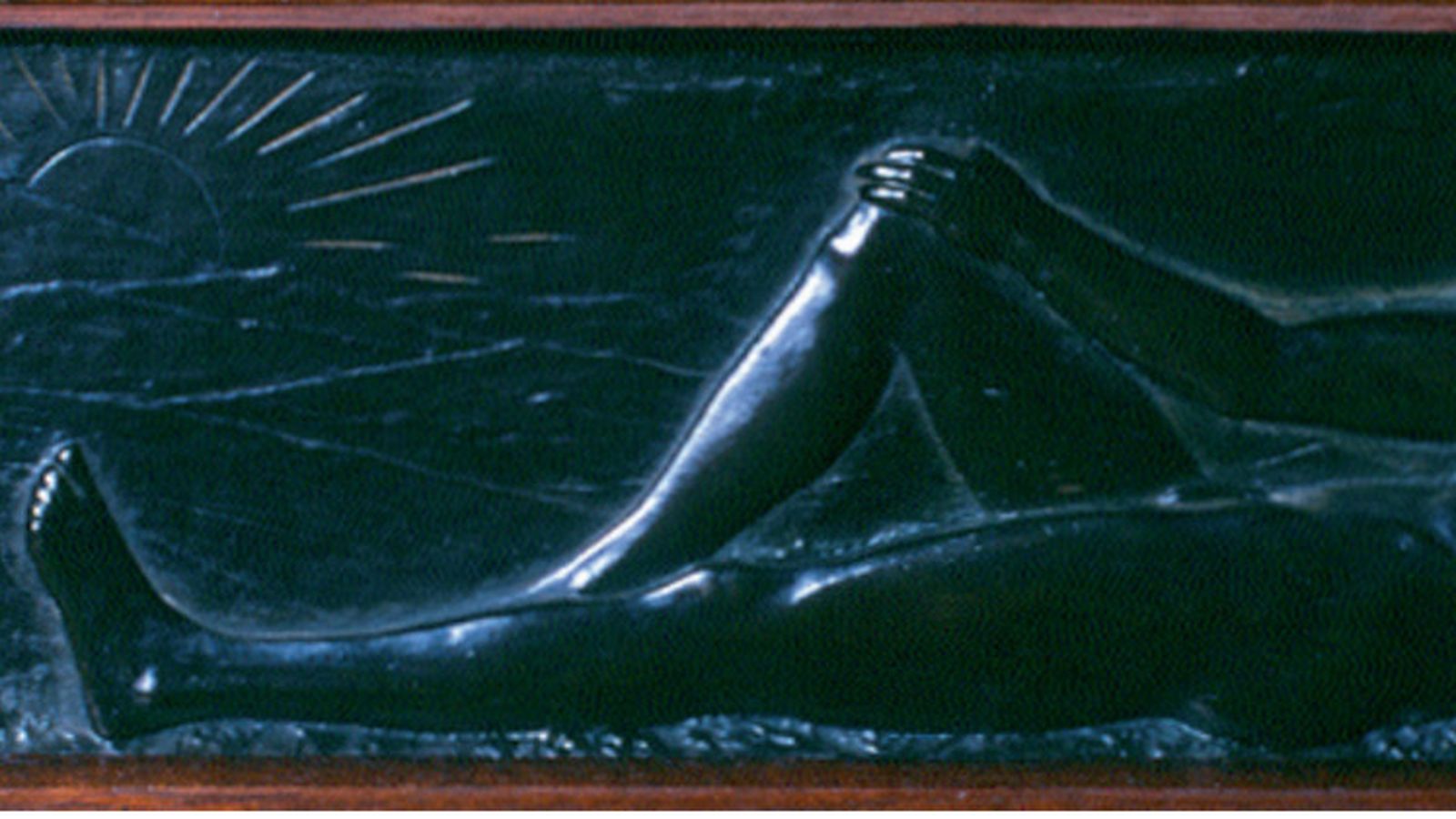 Relieve en bronce situado en la parte inferior izquierda de la pieza que muestra a un hombre que descansa plácidamente mientras contempla un luminoso amanecer observado por una lechuza que está flanqueada por dos cipreses.