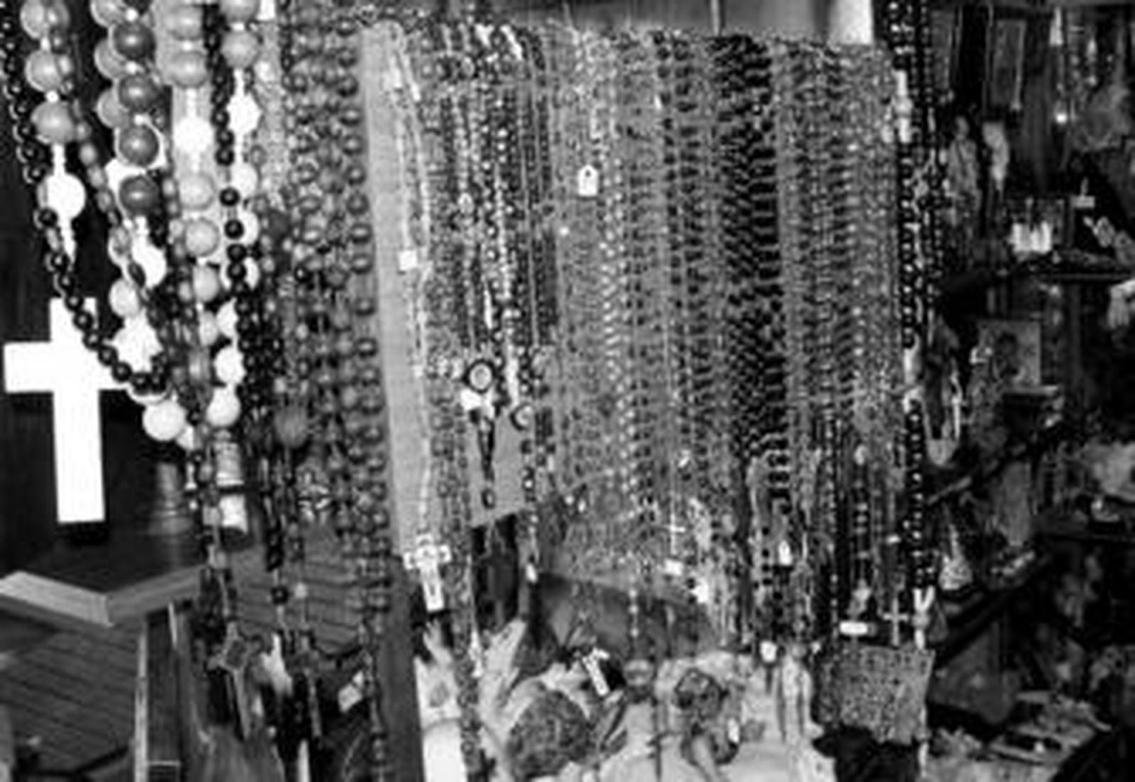 Los rosarios de diferentes Santos y Vírgenes cuelgan de las estanterías llenas de imágenes religiosas.