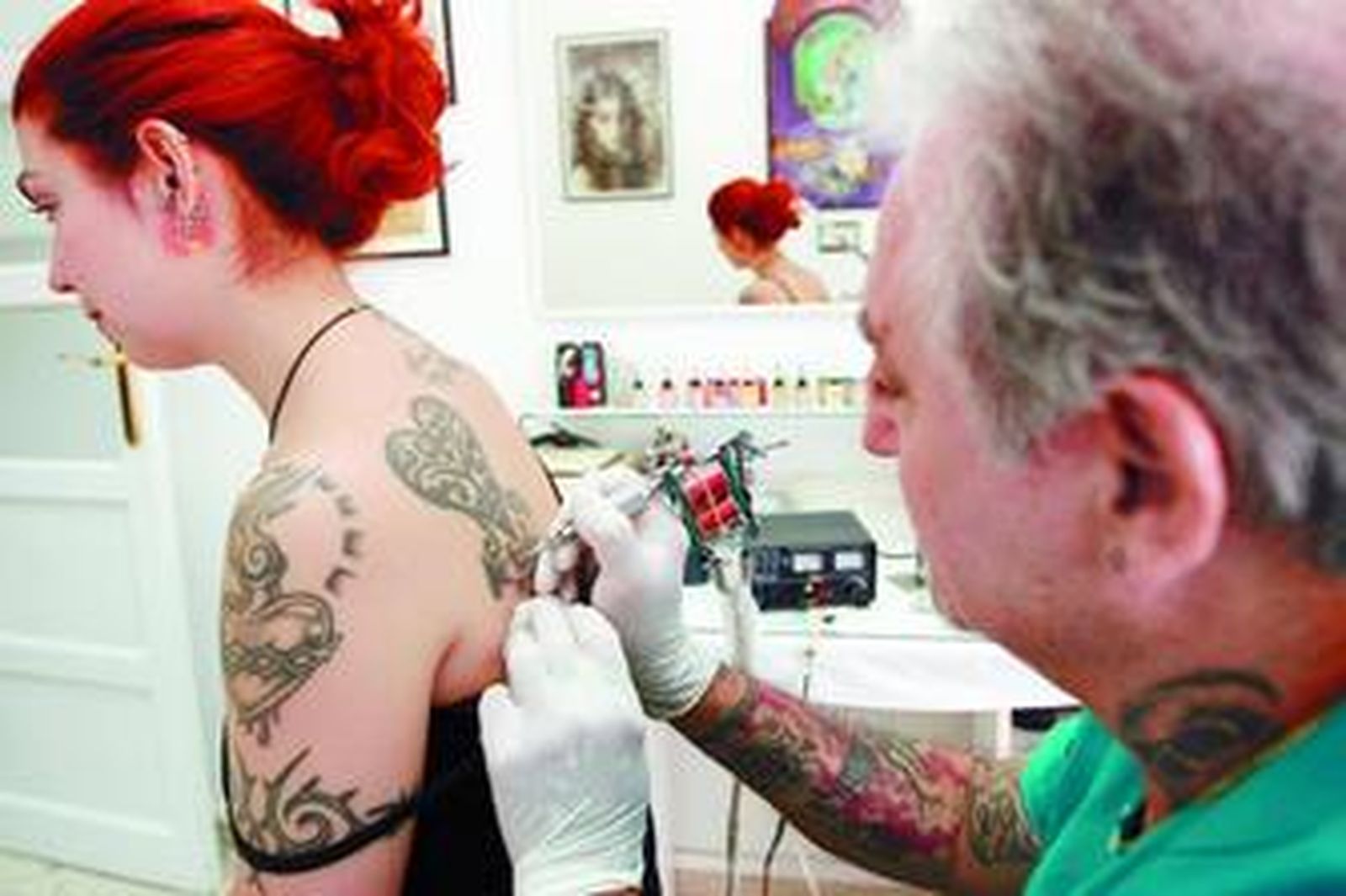 Un tatuador, durante la realización de un dibujo en la espalda de una joven.