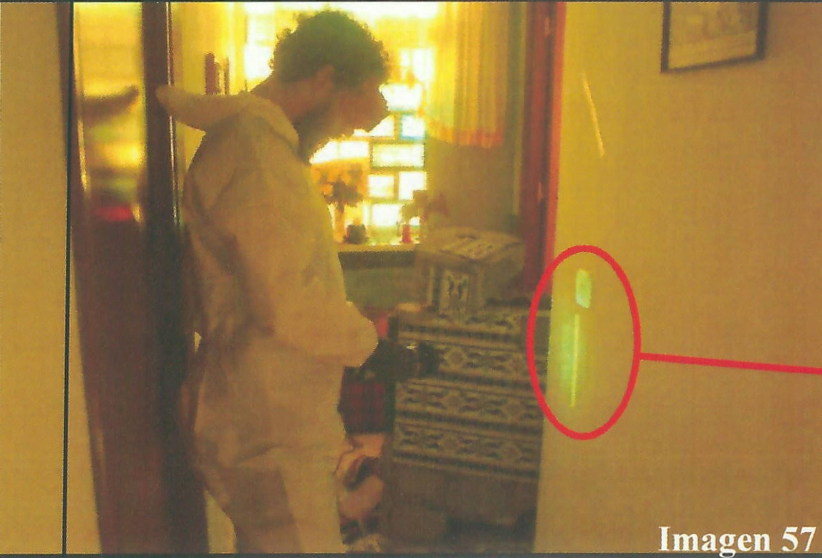 Uno de los agentes del Servicio de Criminalística de la Guardia Civil toma fotografías de una huella encontrada en el pasillo.