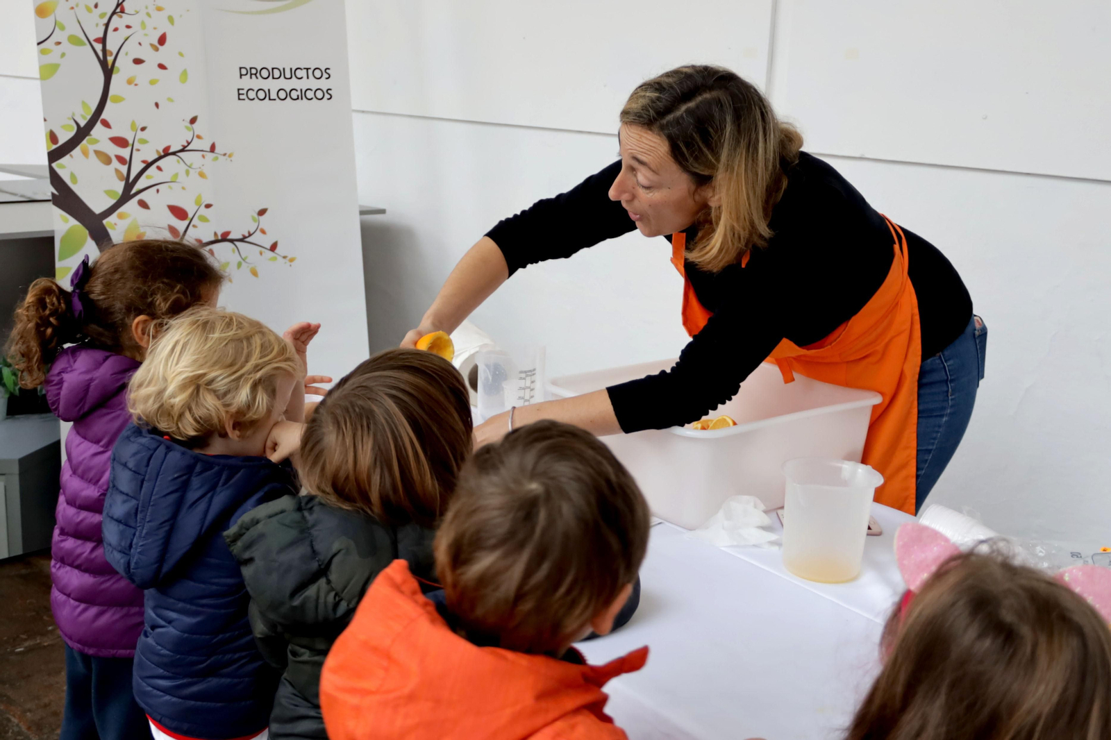 Un grupo de niños exprimen naranjas durante la feria.