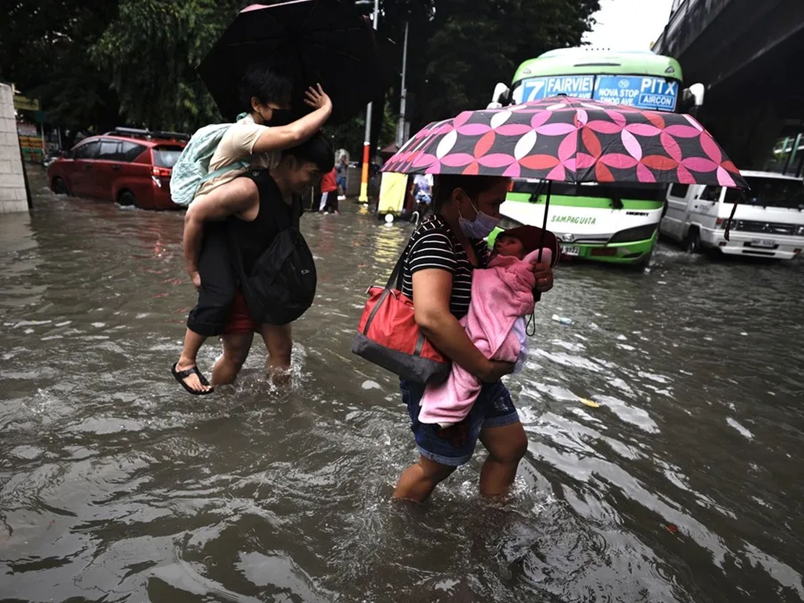 Una familia cruza la calle en plena inundación en Filipinas.