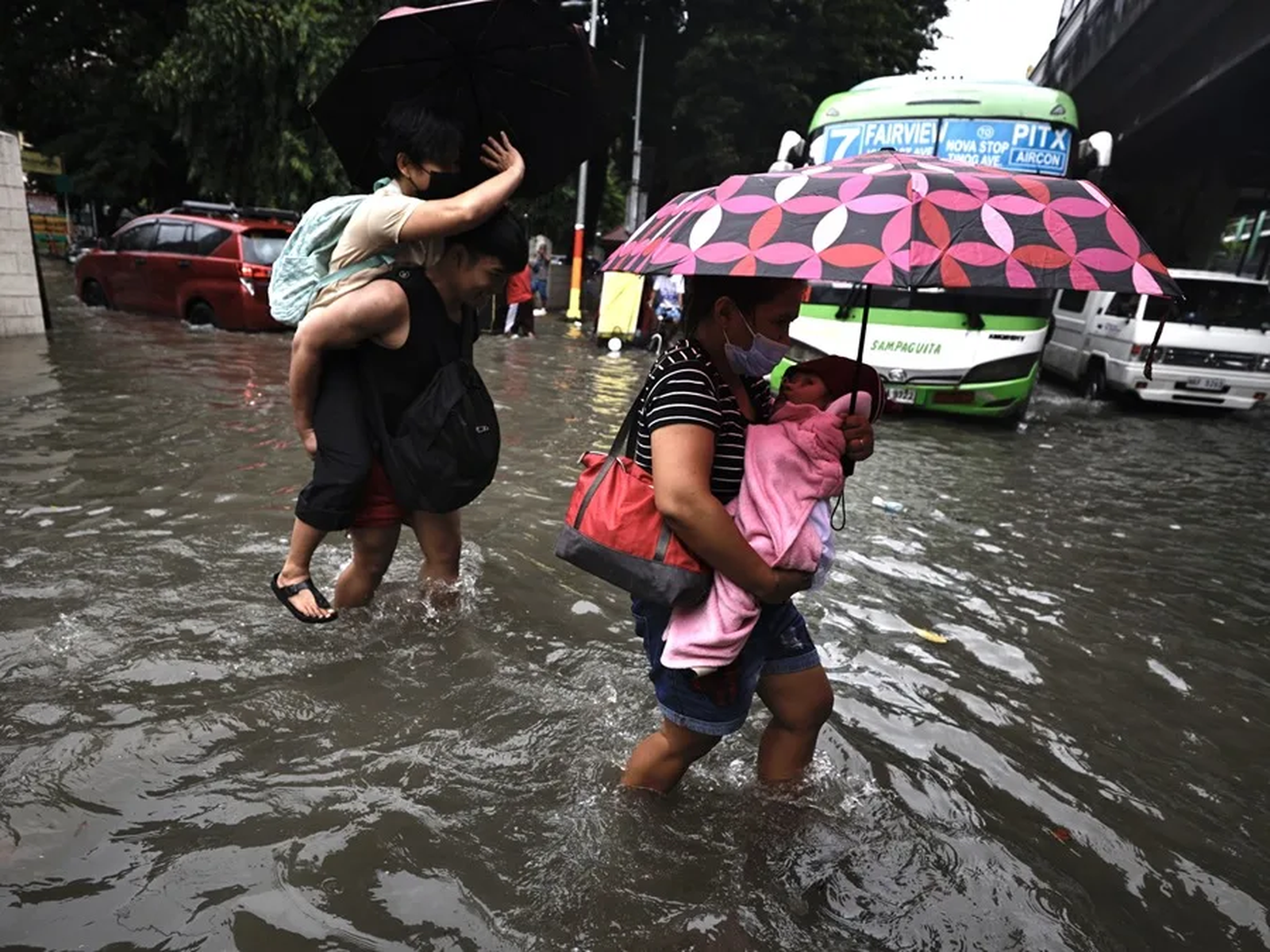 Una familia cruza la calle en plena inundación en Filipinas.