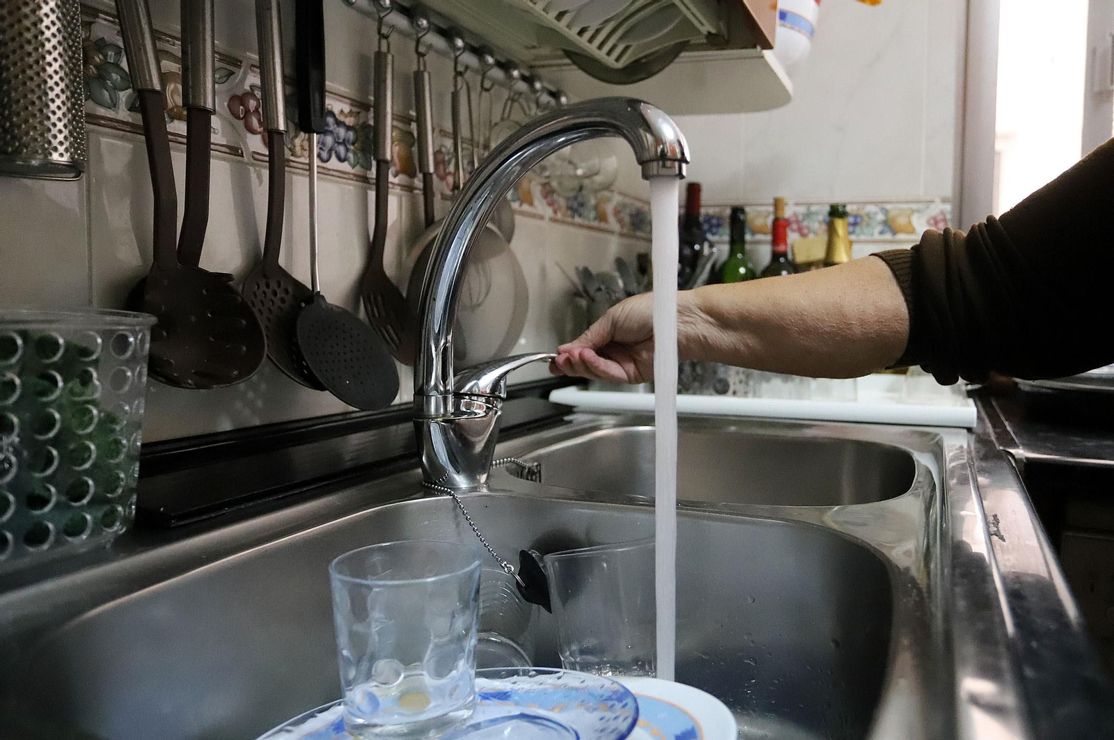 Una mujer abre el grifo en su casa.