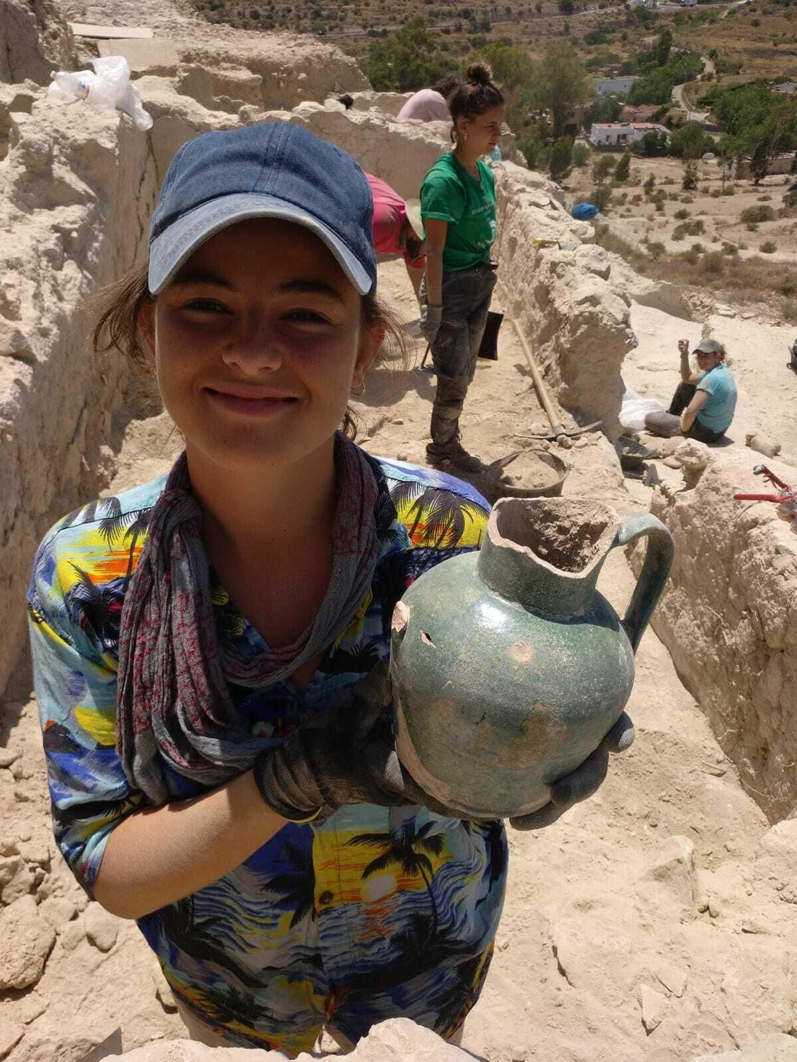 Una de las arqueólogas muestra la jarra hallada.