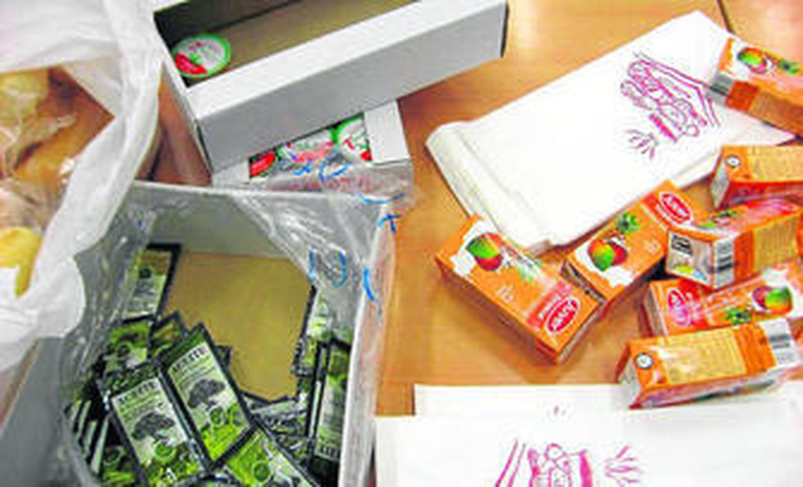 Cajas con pan, aceite y zumos que recibieron ayer en algunos colegios.