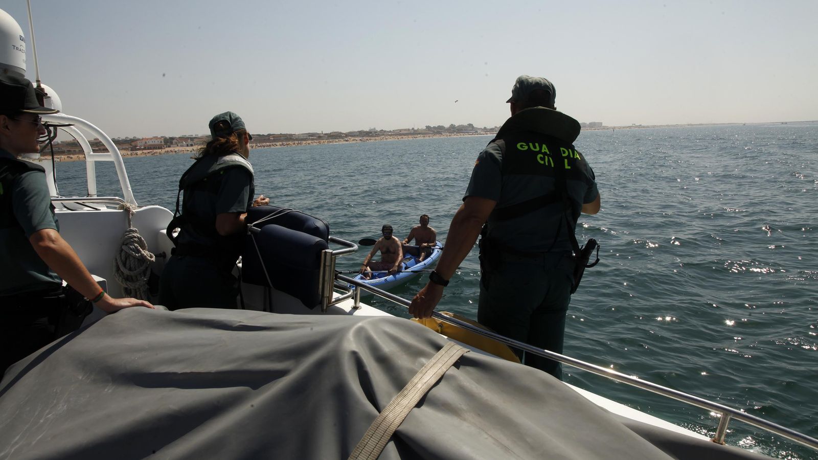 Los Guardias Civiles adiverten a dos hombres que navegan en kayak sin chaleco salvavidas de la necesidad de usar el mismo en todo momento.