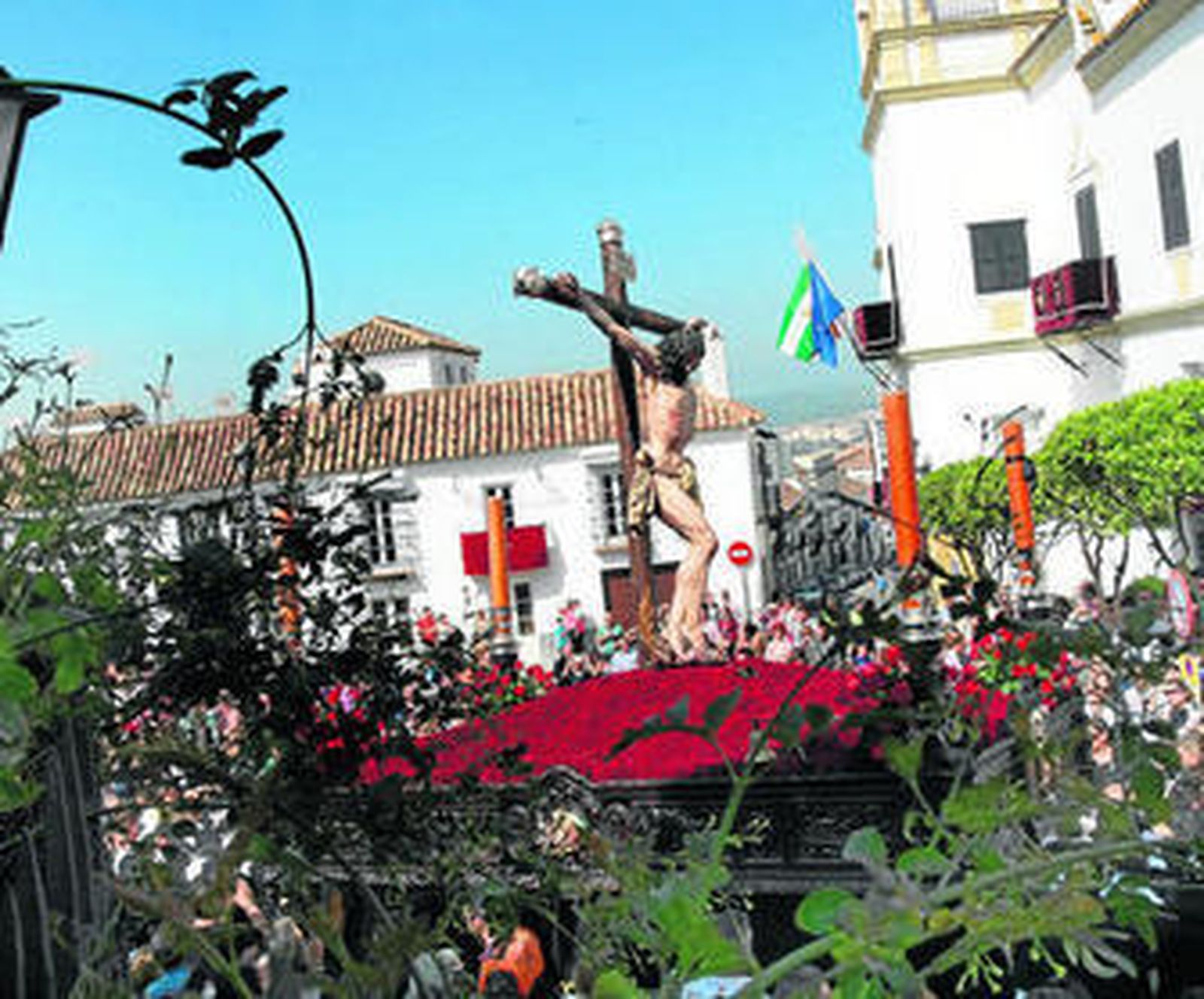 La talla del Cristo en la Plaza de la iglesia (i), detalles de la escarapela del Ejército en un cargador de la Virgen, uno de los enseres y los pies del Buena Muerte sobre claveles rojos y la rosa negra.