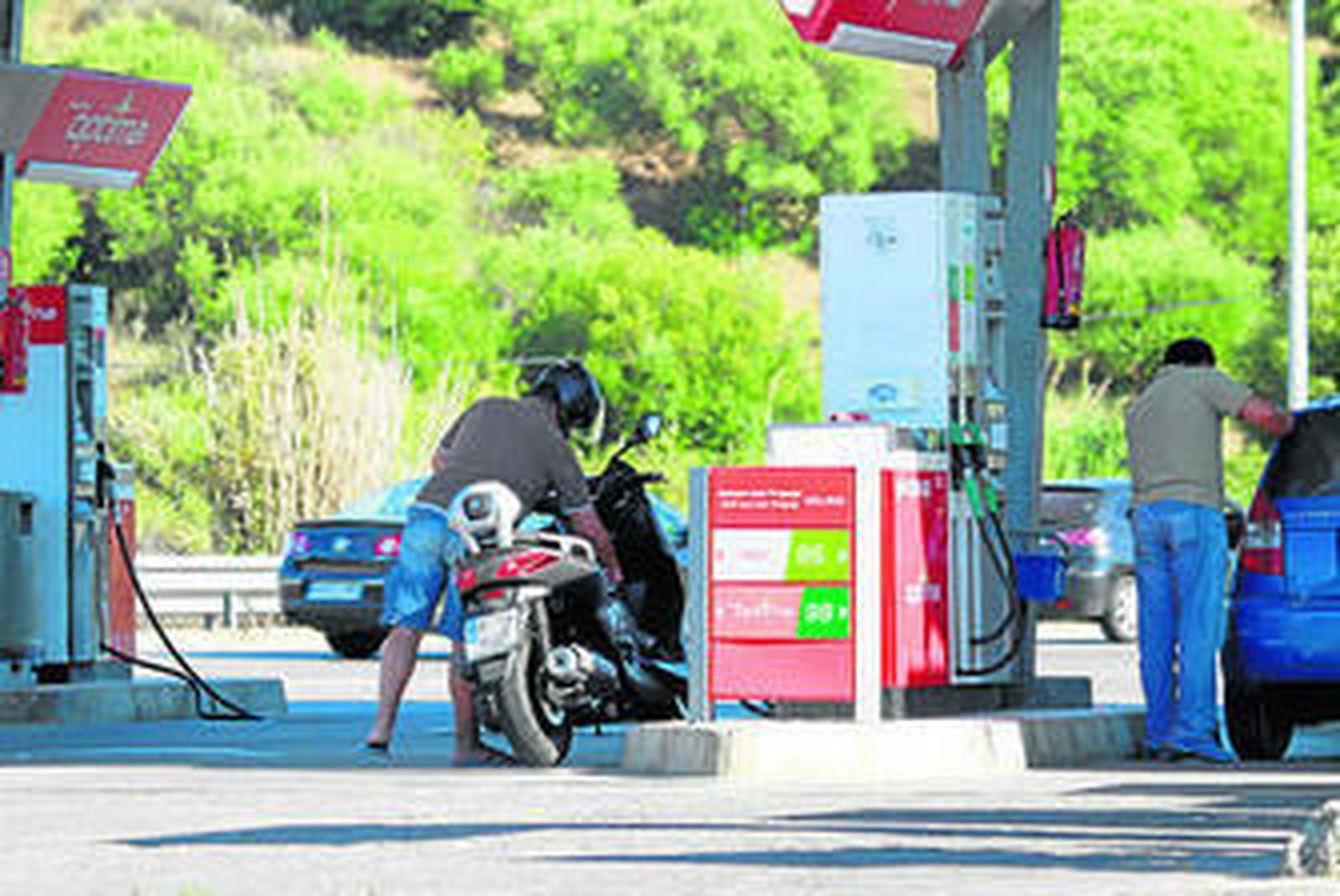 Varias personas repostan sus vehículos en la gasolinera Las Rosas, ayer.