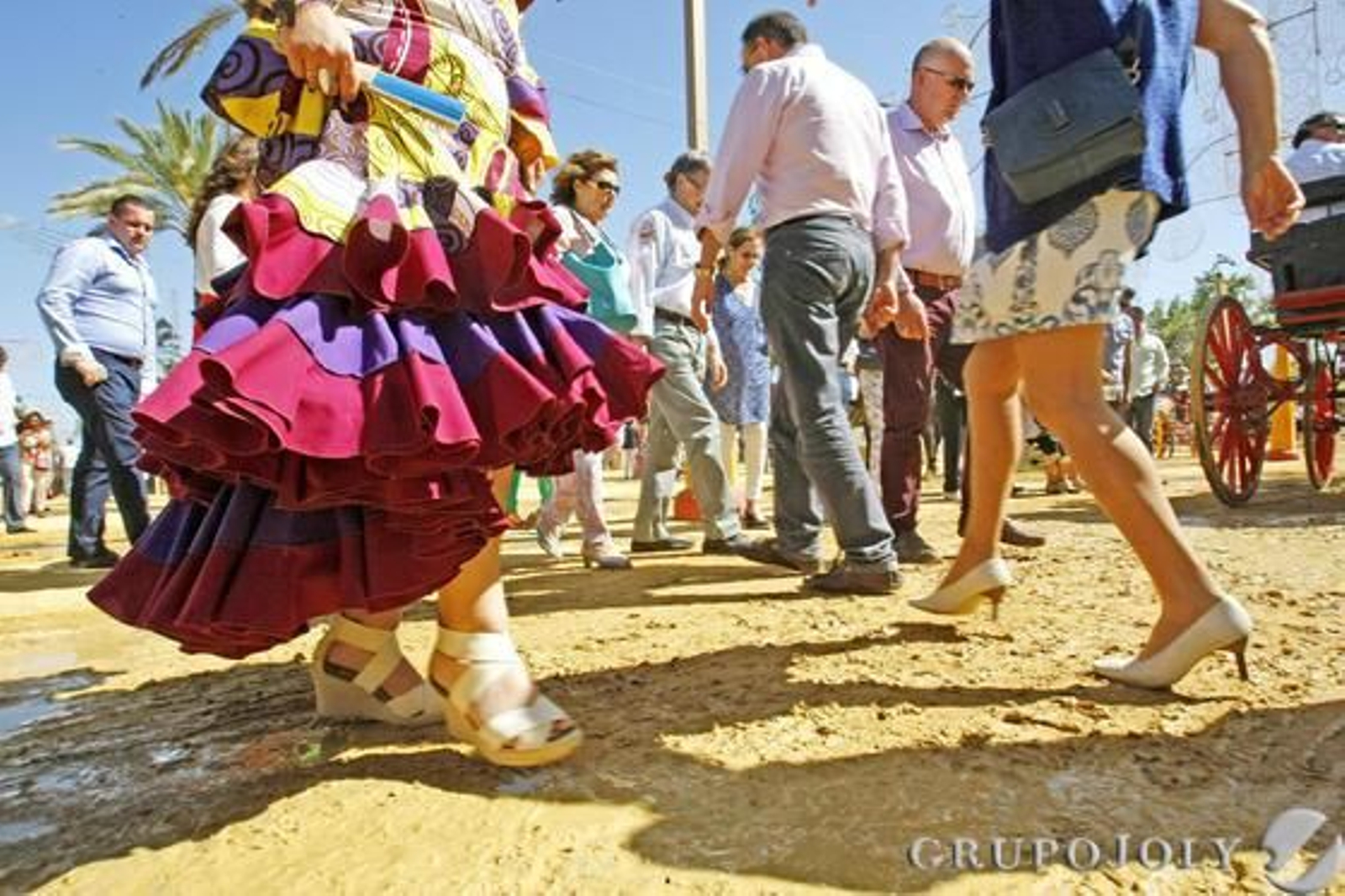 Una mujer vestida de flamenca se remanga el vestido al pasar por una zona enfangada.  Foto: Pascual