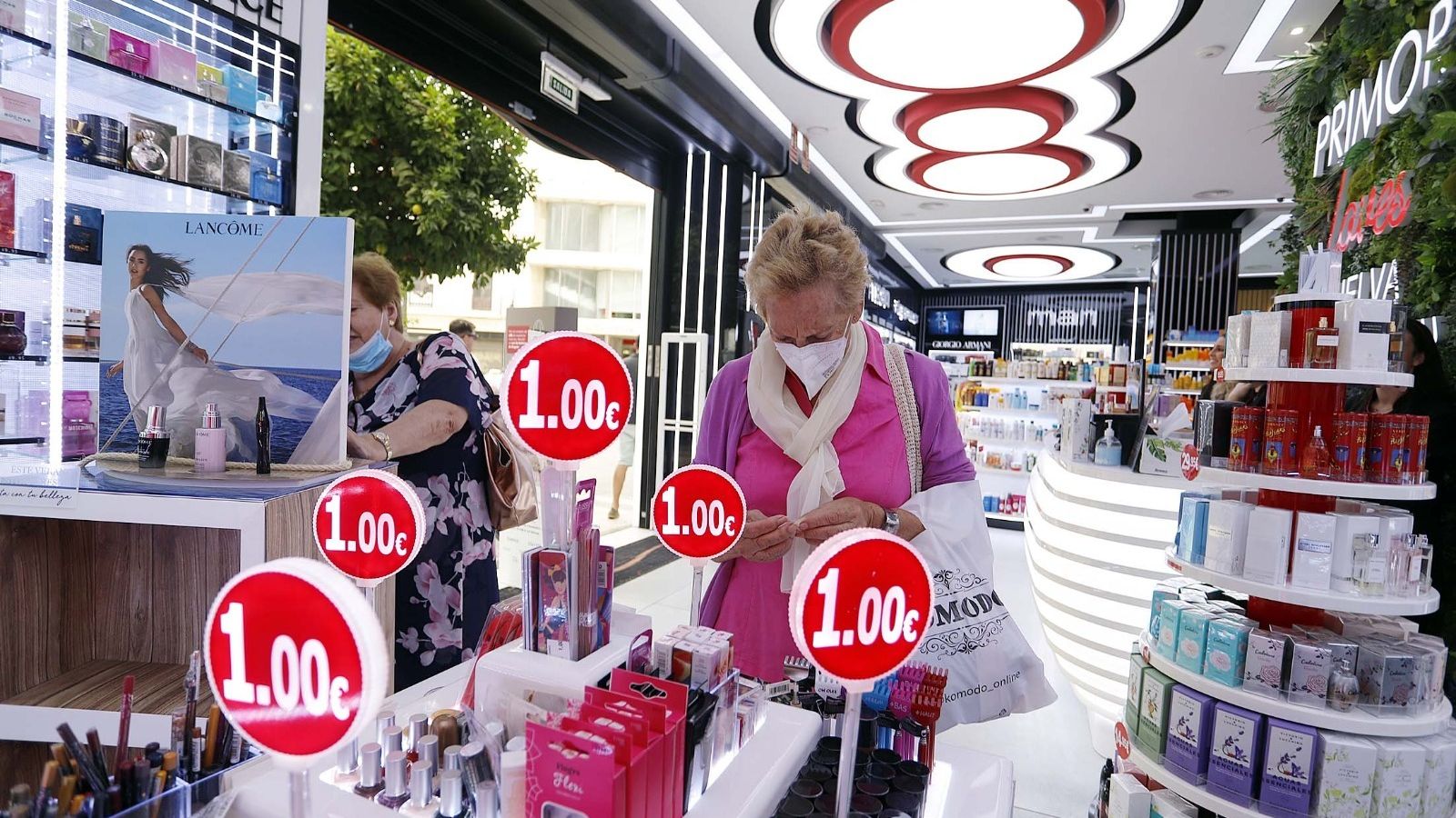 Una clienta revisa un expositivo con artículos más rebajados en una perfumería.