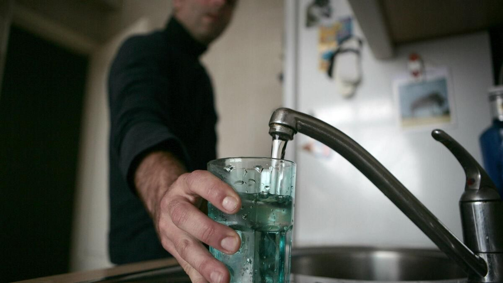 Un hombre llena un vaso de agua.