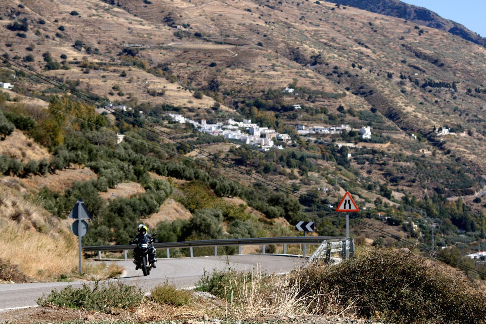 Una moto por una carretera de la Alpujarra con Soportújar de fondo