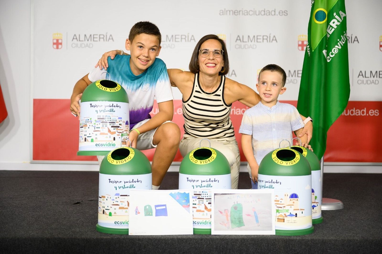La concejala Margarita Cobos entrega los premios a los dos niños campeones del concurso de dibujo de Ecovidrio
