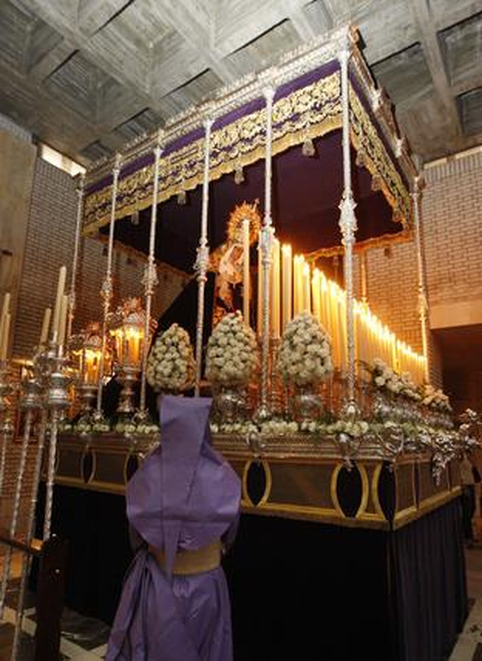 Un nazareno de la Defensión frente al palio de La O.

Foto: Juan Carlos Toro